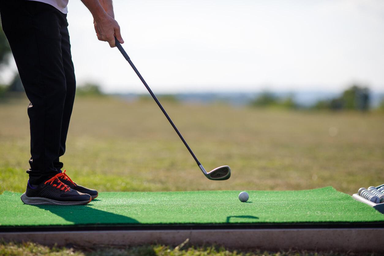 A golf club lining up to hit the ball on a golf course