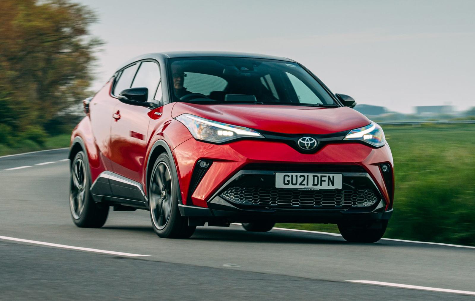 a red toyota c-hr driving on a country road