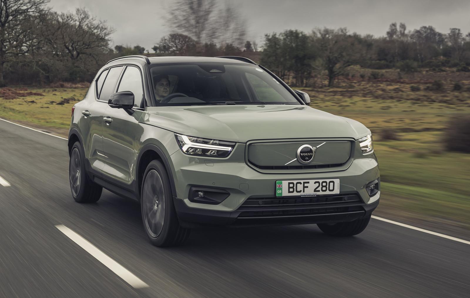 a green volvo xc40 driving on a road