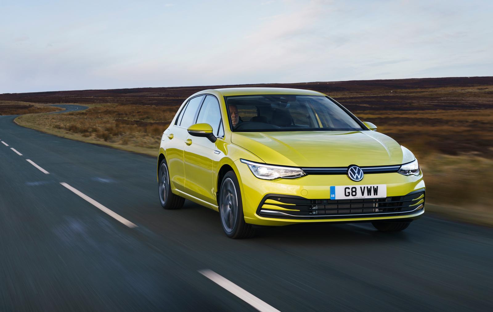 a yellow Vw Golf mk8 driving on an empty country road