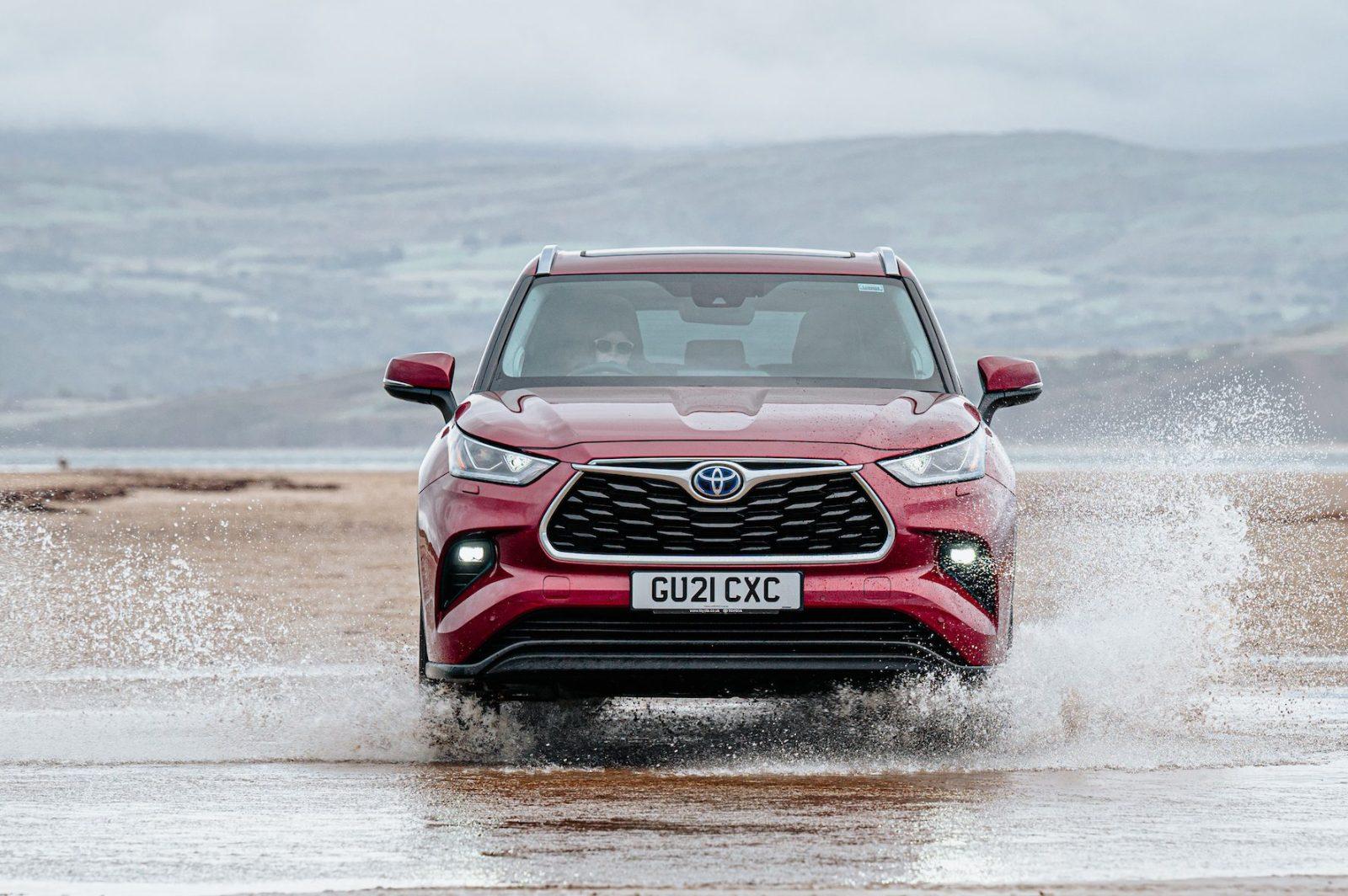 A burgundy Toyota Highlander driving through water