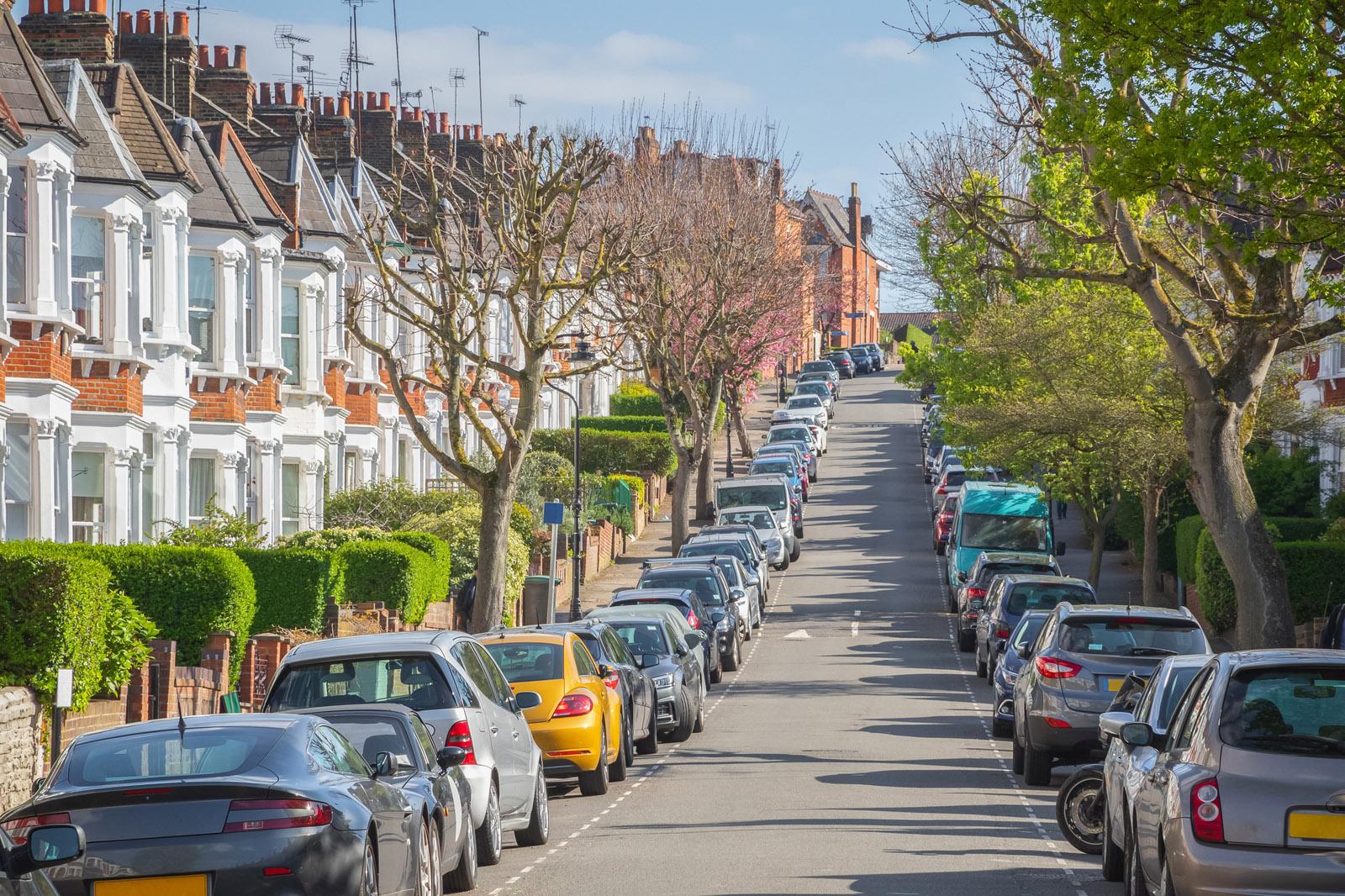 a busy UK street with cars parked on either side