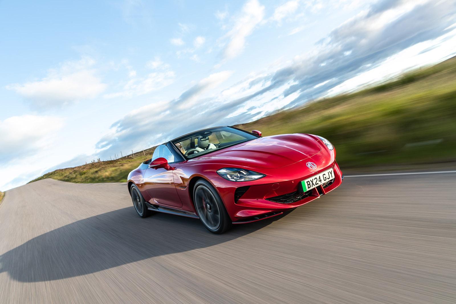 a red MG Cyberster driving on a country road