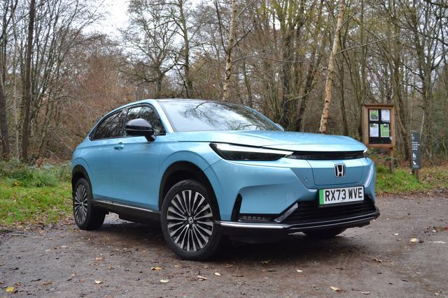 a light blue honda e:ny1 parked in a woods