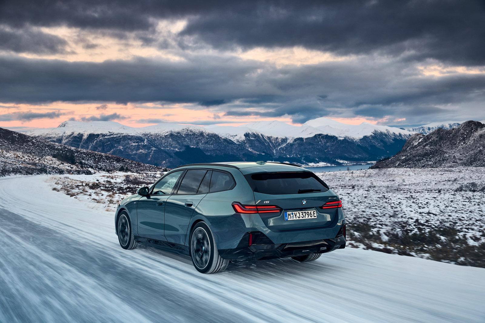 a blue bmw i5 touring driving in the snowy mountains