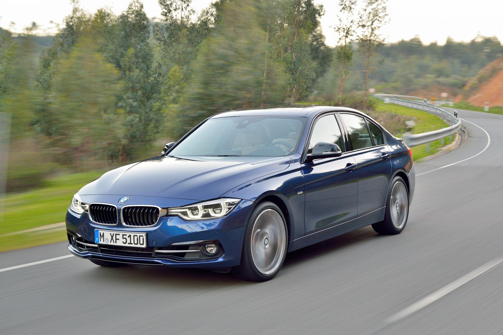 a dark blue BMW 3 Series driving on a road