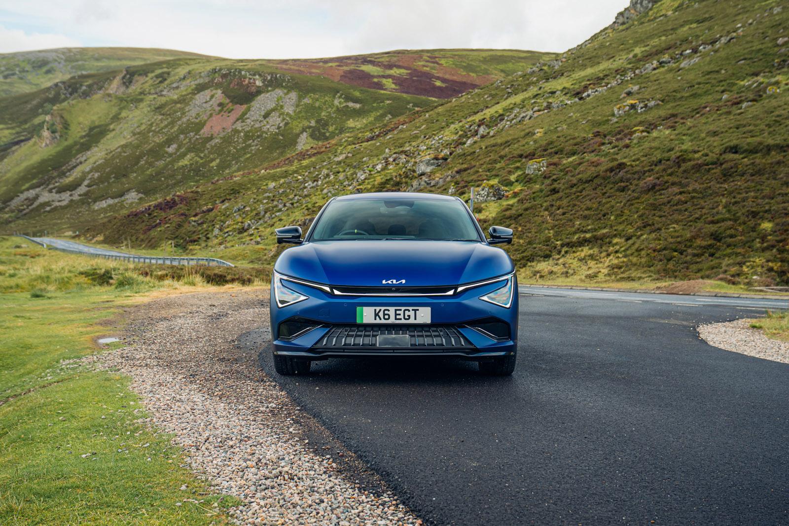Dark blue Kia EV6 GT parked on a road surrounded by mountains