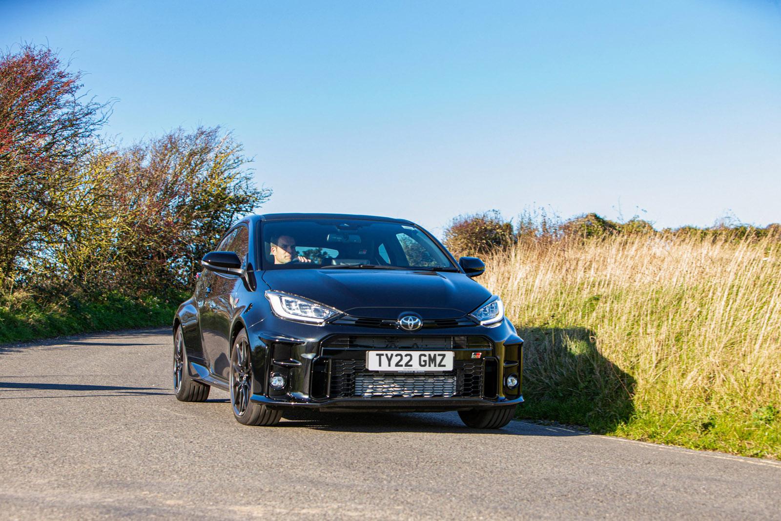 a black toyota gr yaris driving on a country road