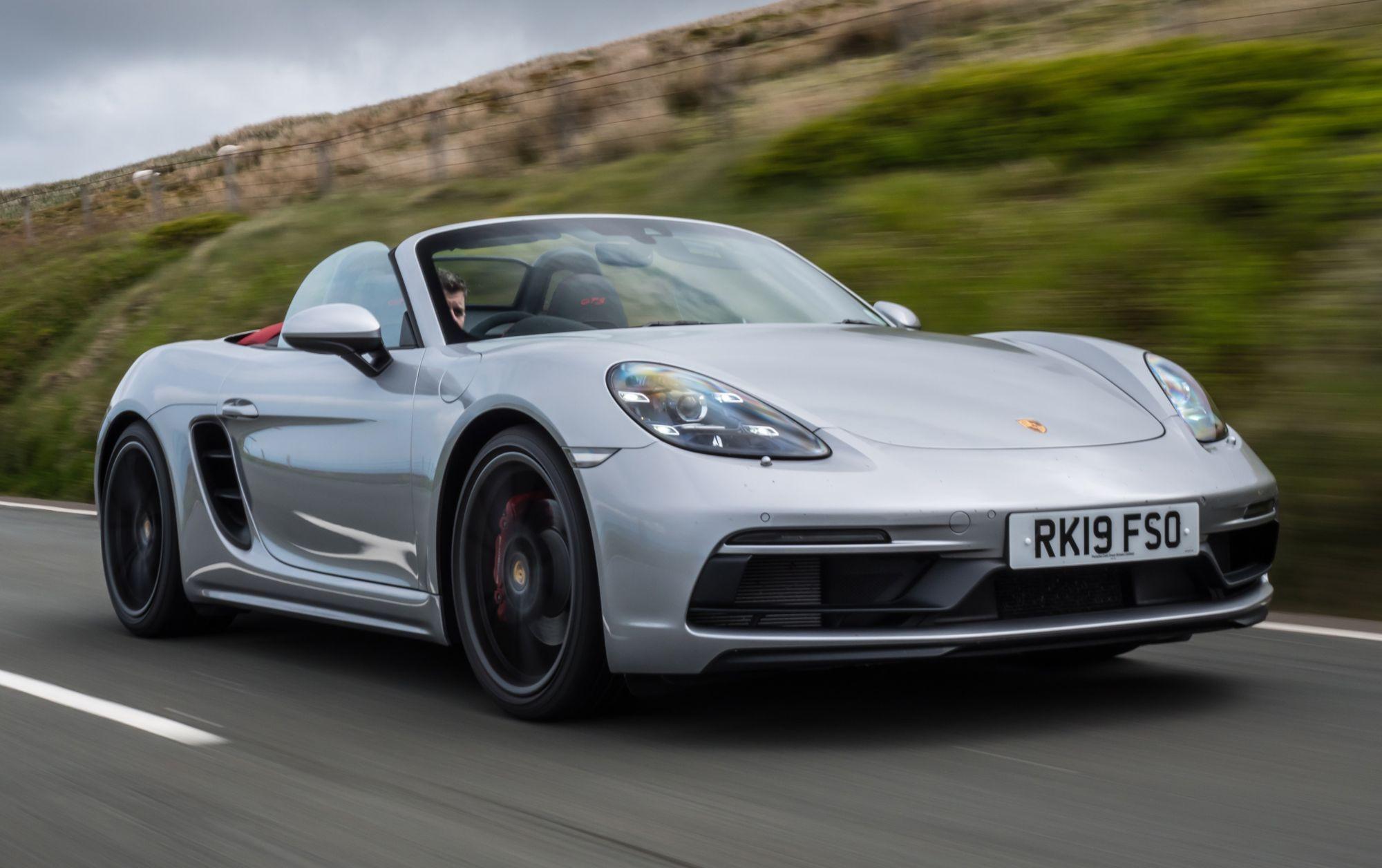 a silver porsche 718 boxster driving on a british road