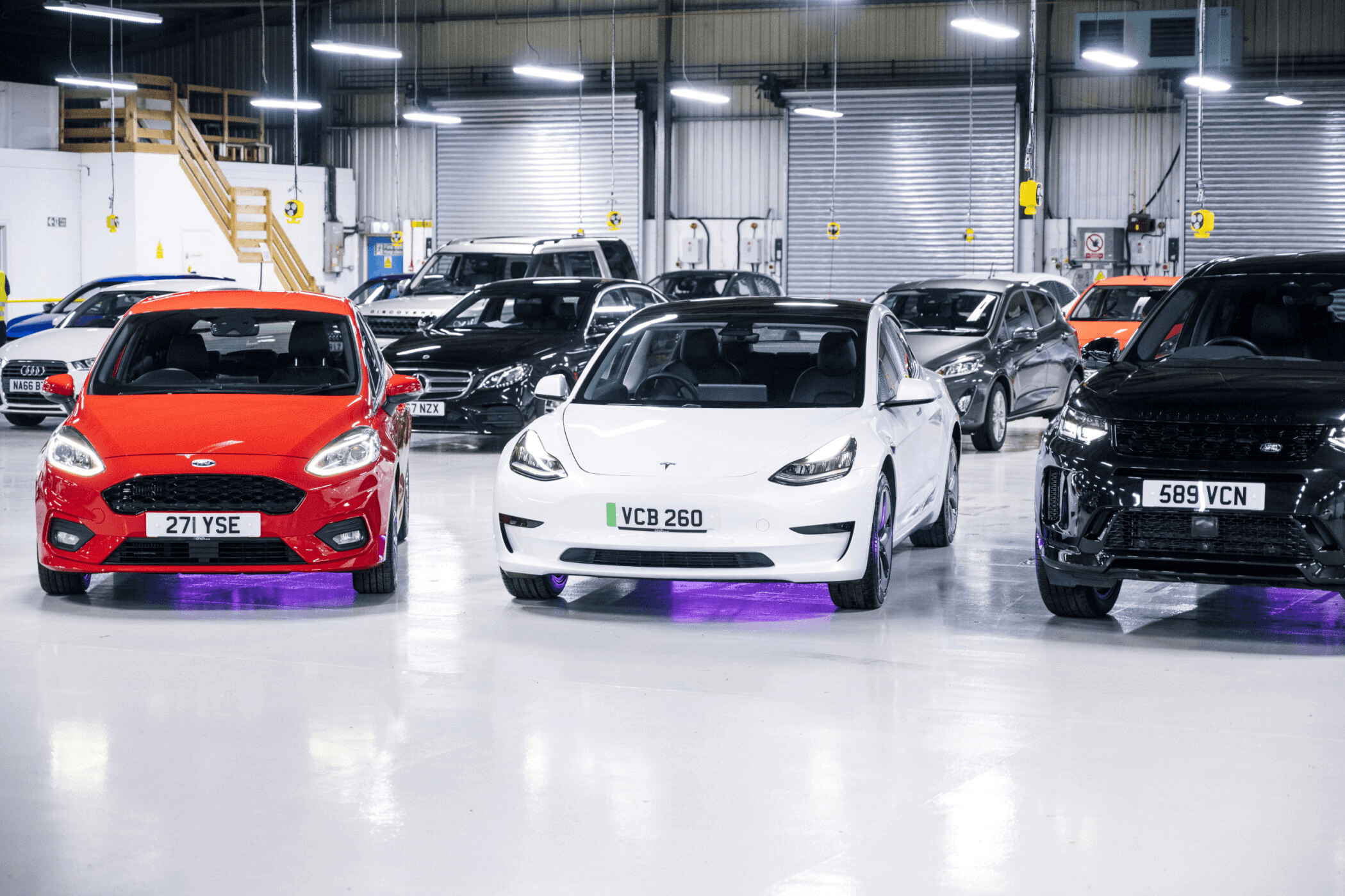 Three cars parked together in a warehouse