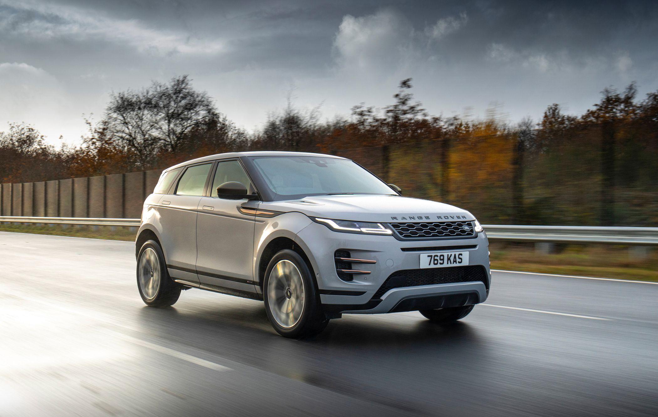 Silver Range Rover Evoque driving on a wet road, with blurred trees and a cloudy sky in the background.