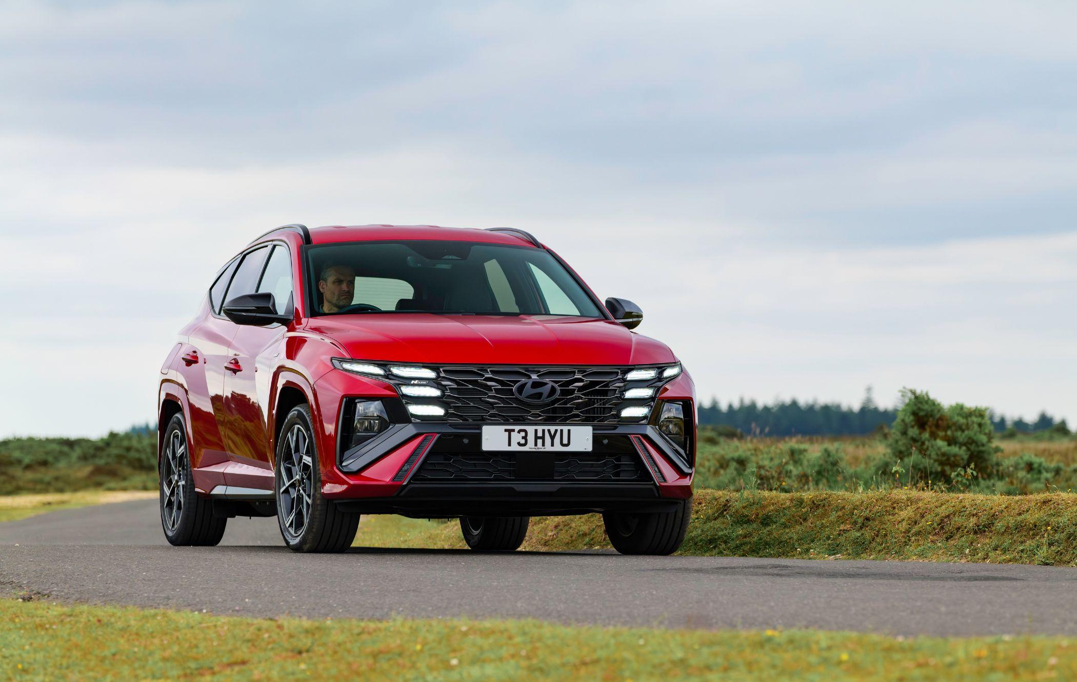 Red Hyundai Tucson N Line driving on country road