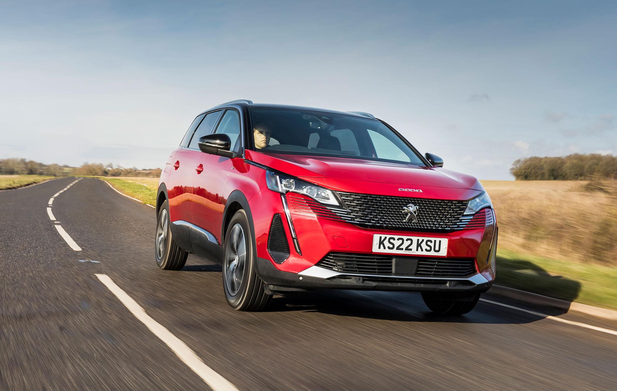 a red peugeot 3008 driving on a road