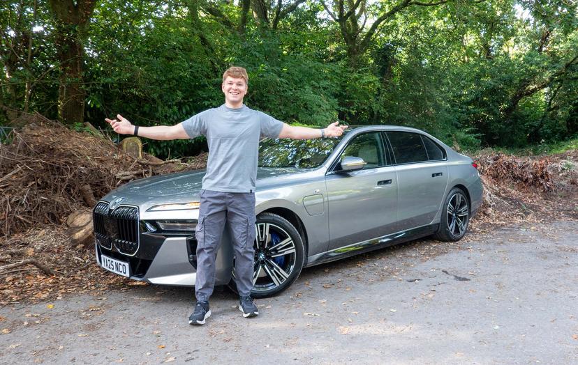 Craig Hale standing in front of a silver BMW 7 Series parked on a leafy roadside.