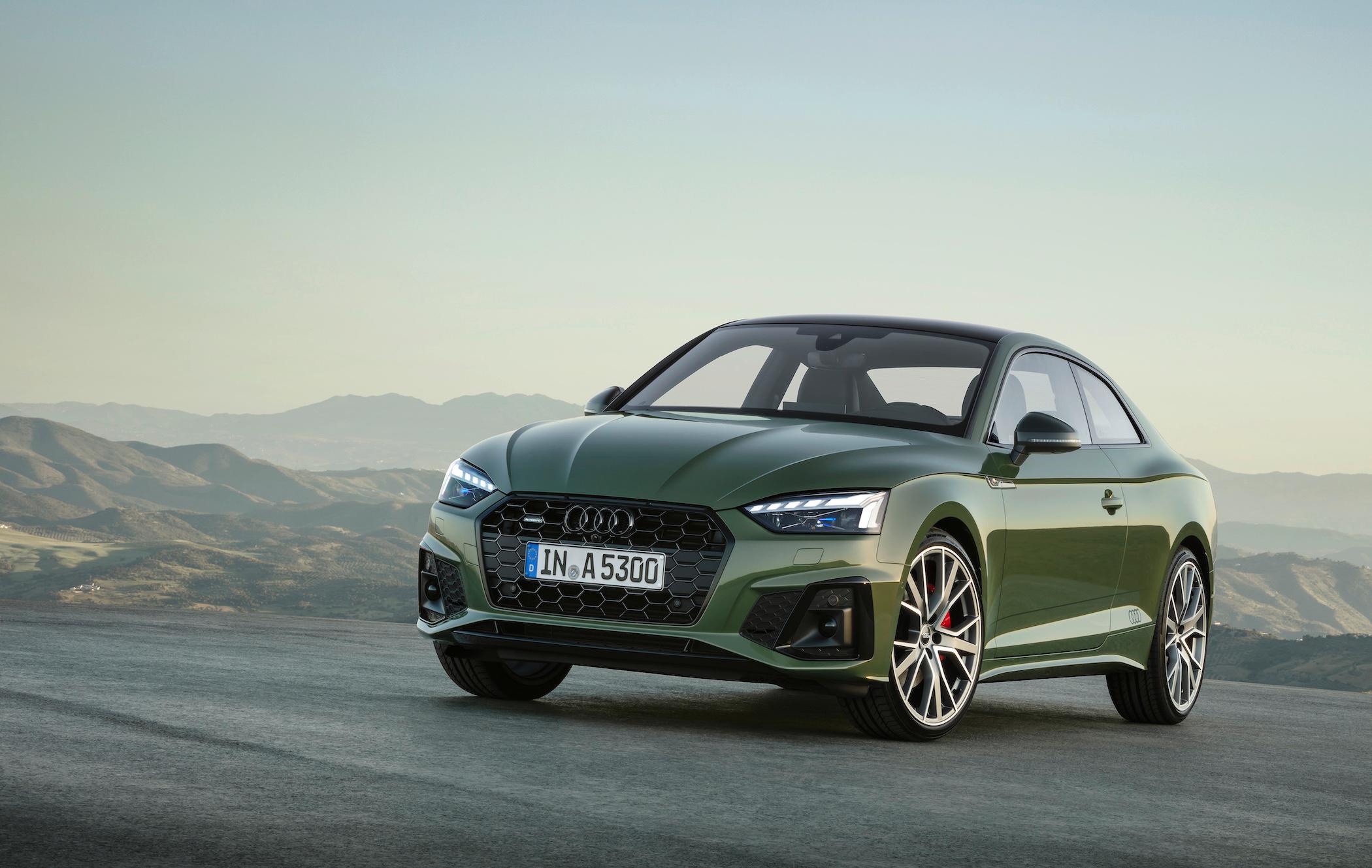 a dark green audi a5 parked on a road overlooking some mountains