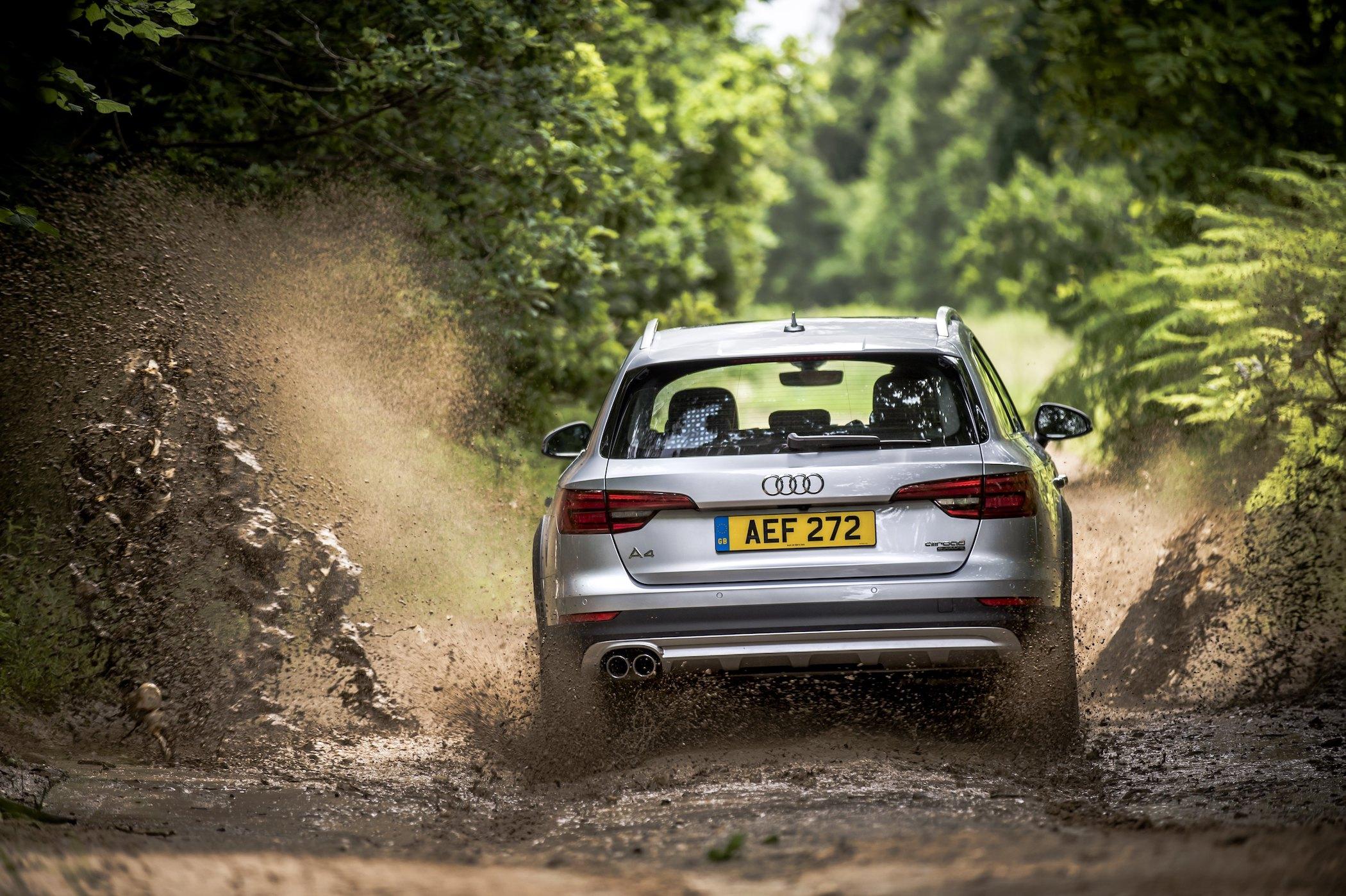 a silver audi a4 allroad driving through muddy water in a forest