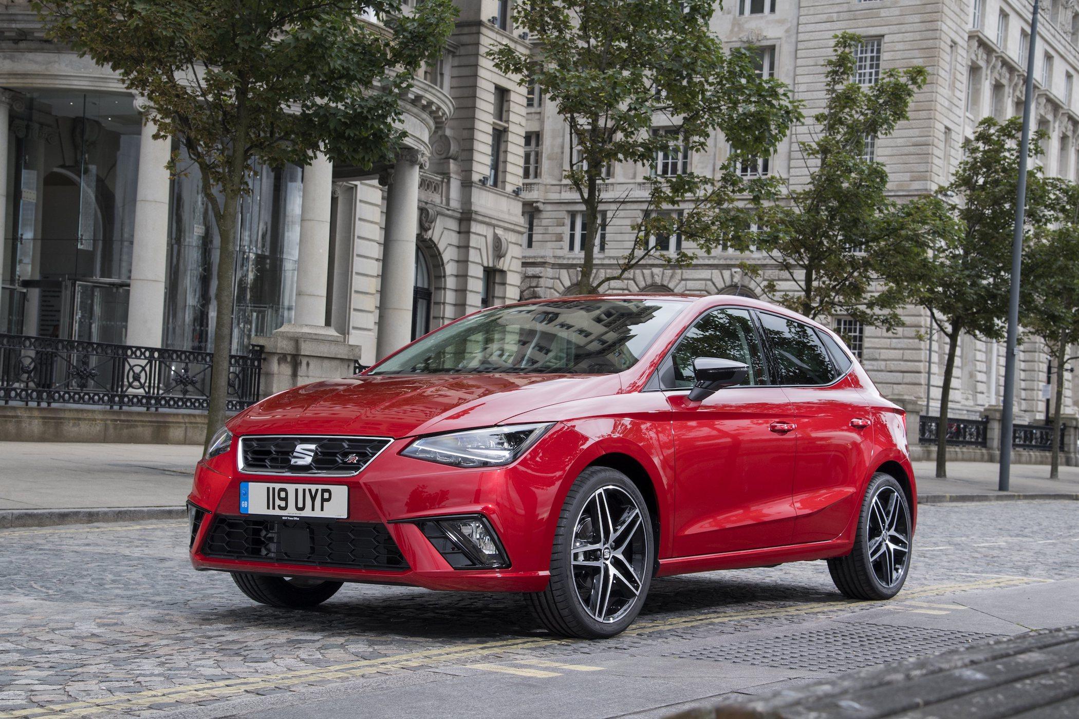 a red seat ibiza driving through a city