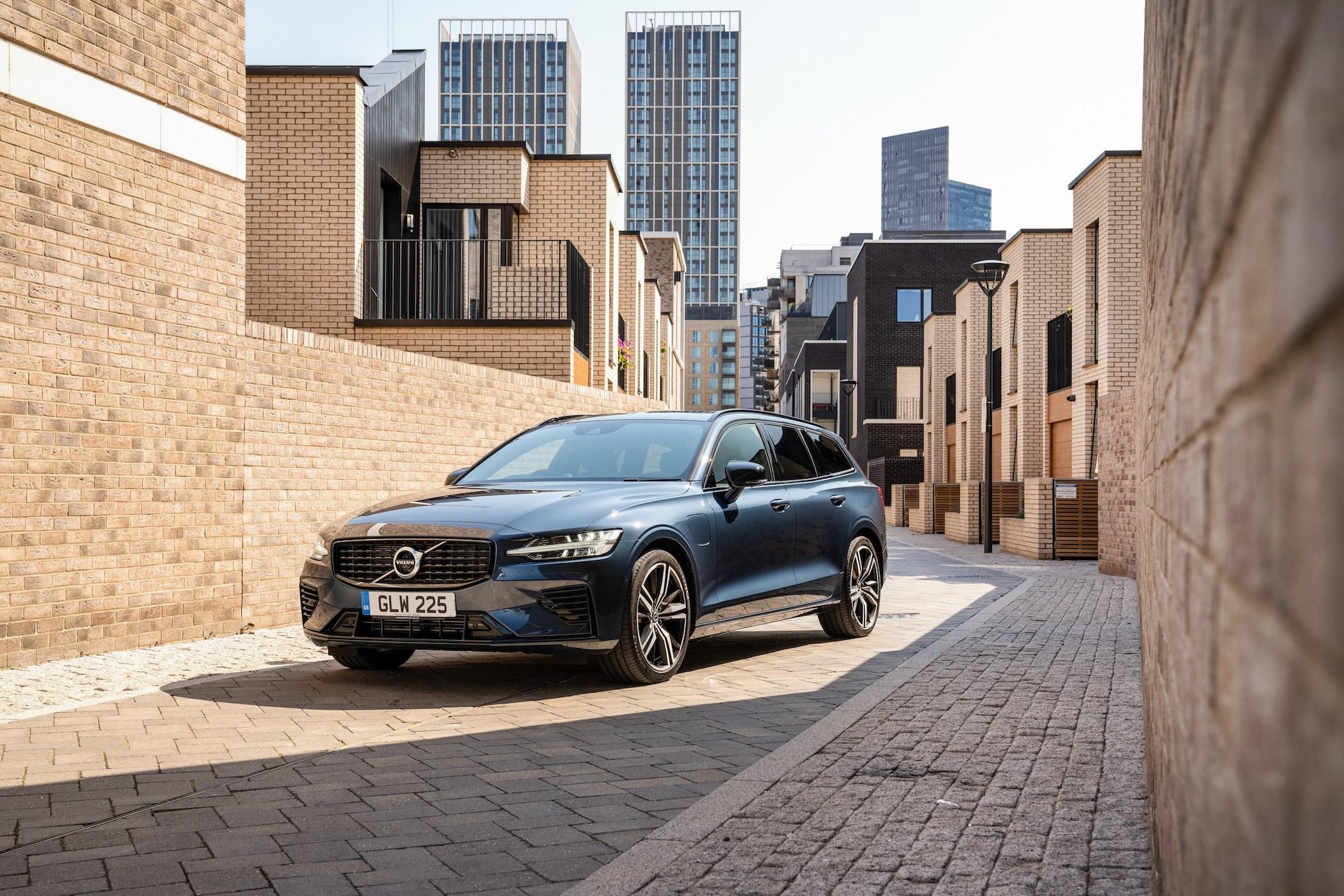 a blue volvo v60 recharge facing the camera, parked on a narrow street in a city