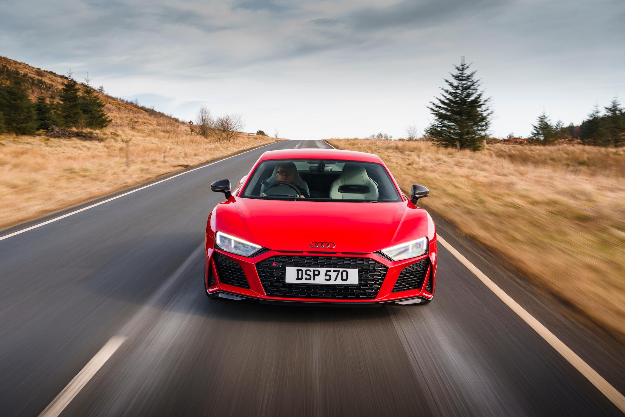 a red audi r8 v10 plus driving on a long country road