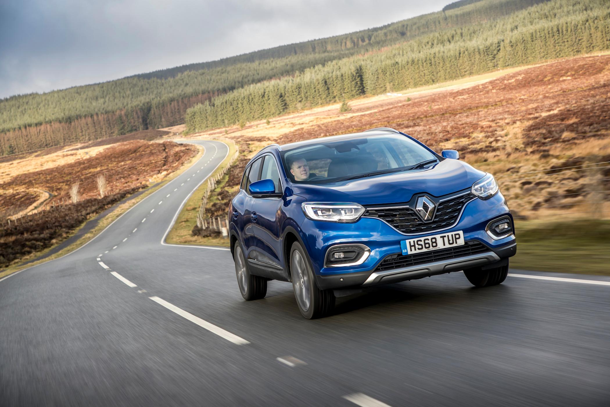 a dark blue renault kadjar driving on a country road