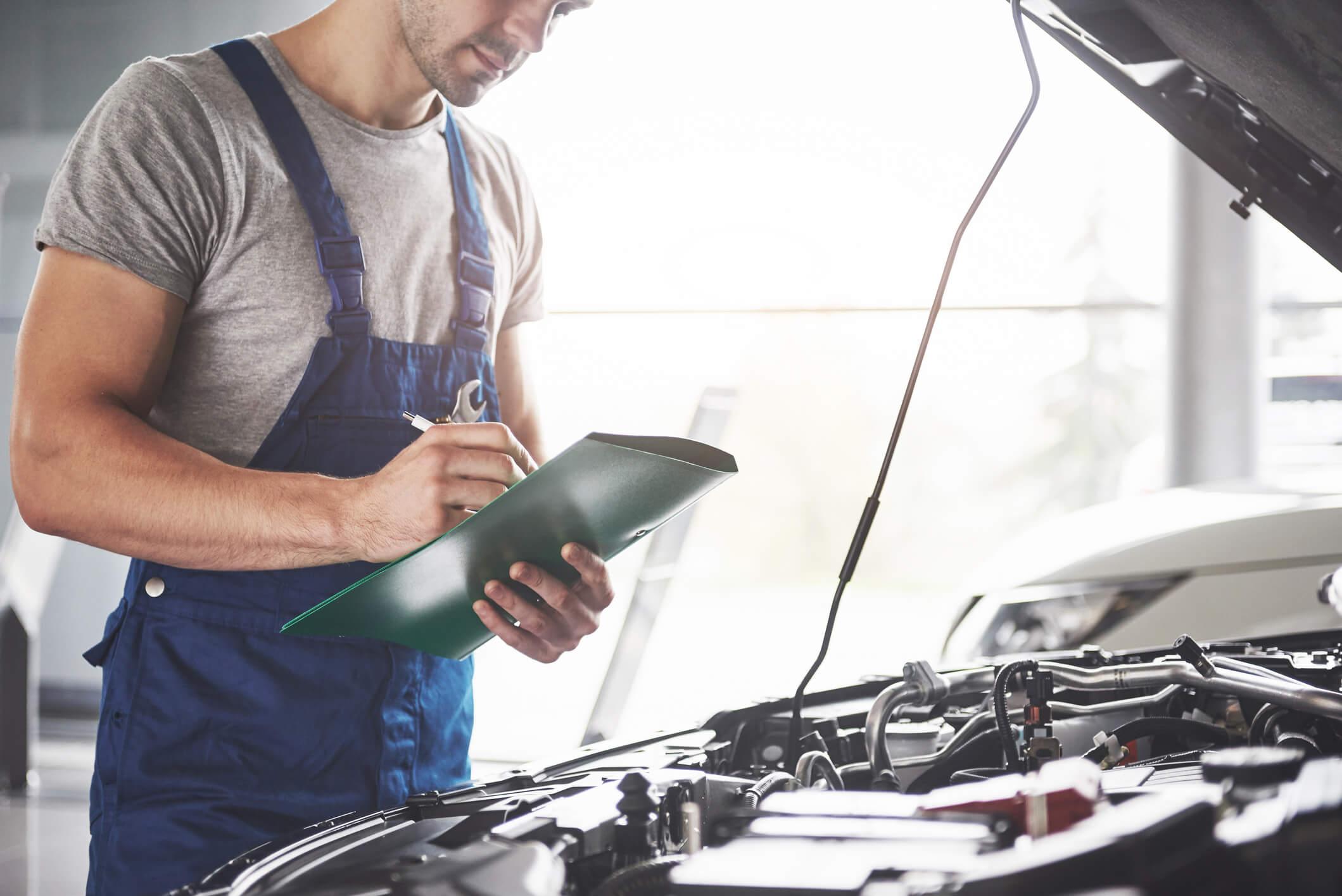 A man with a clipboard inspecting a car