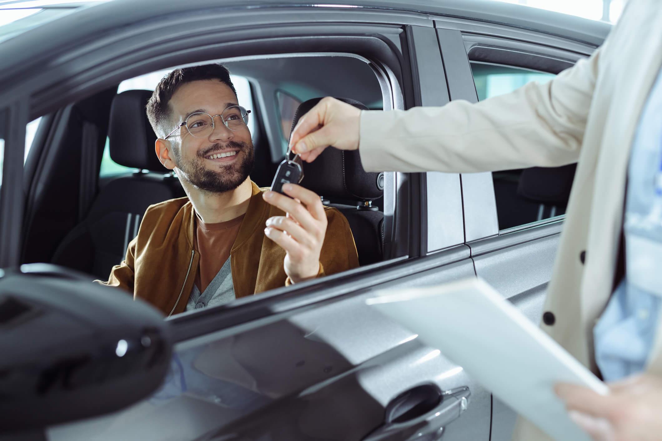 A man sitting in a car being passed a car key