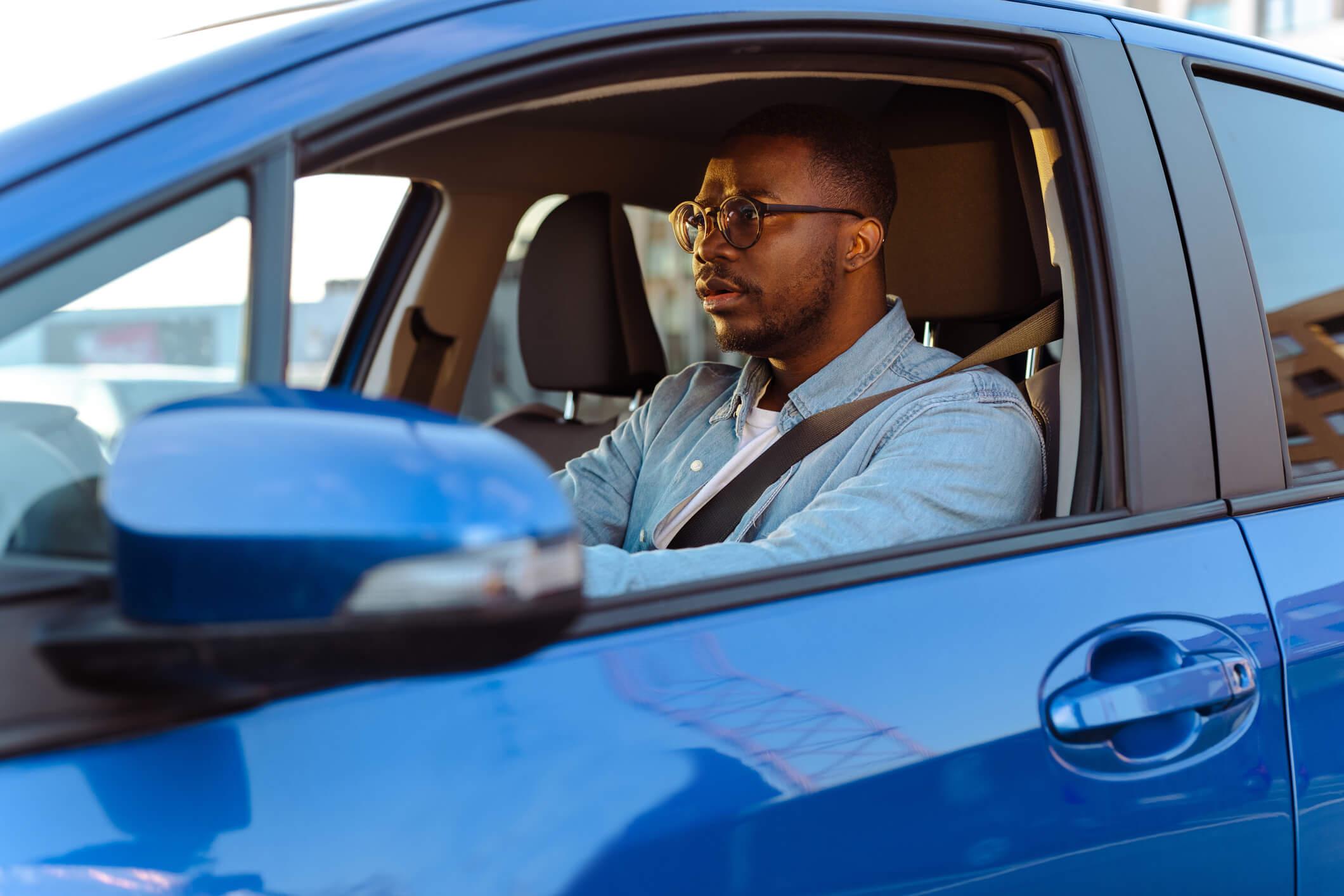 A man looking nervous while driving a car