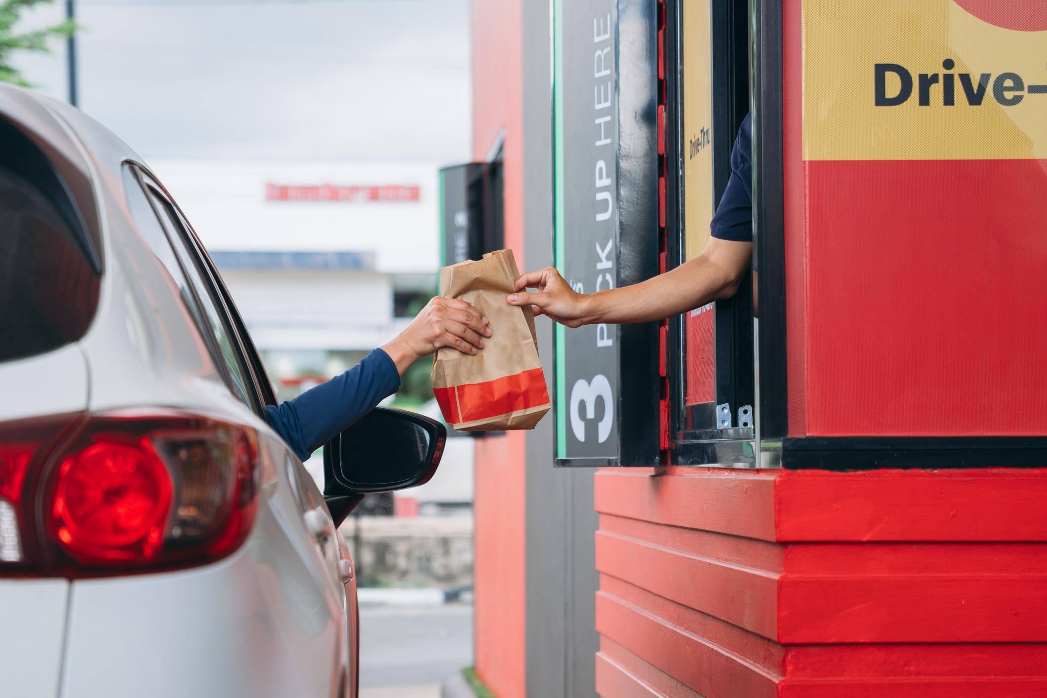 A car parked next to a drive-thru window collecting their order