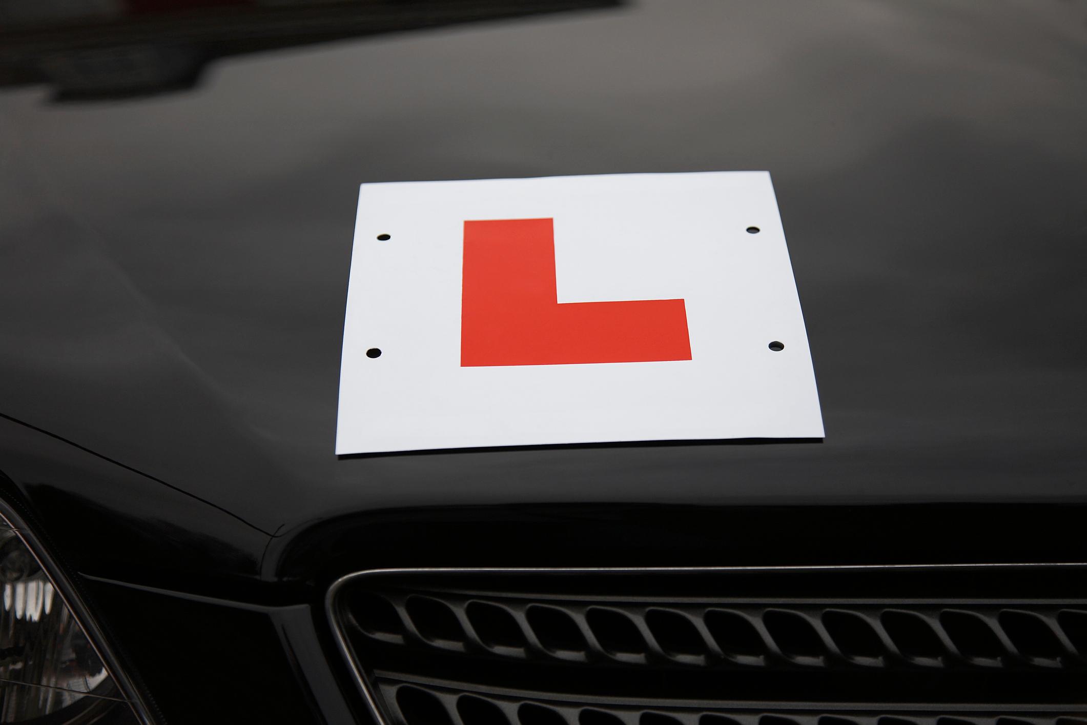 A red 'L' plate on the front of a black car