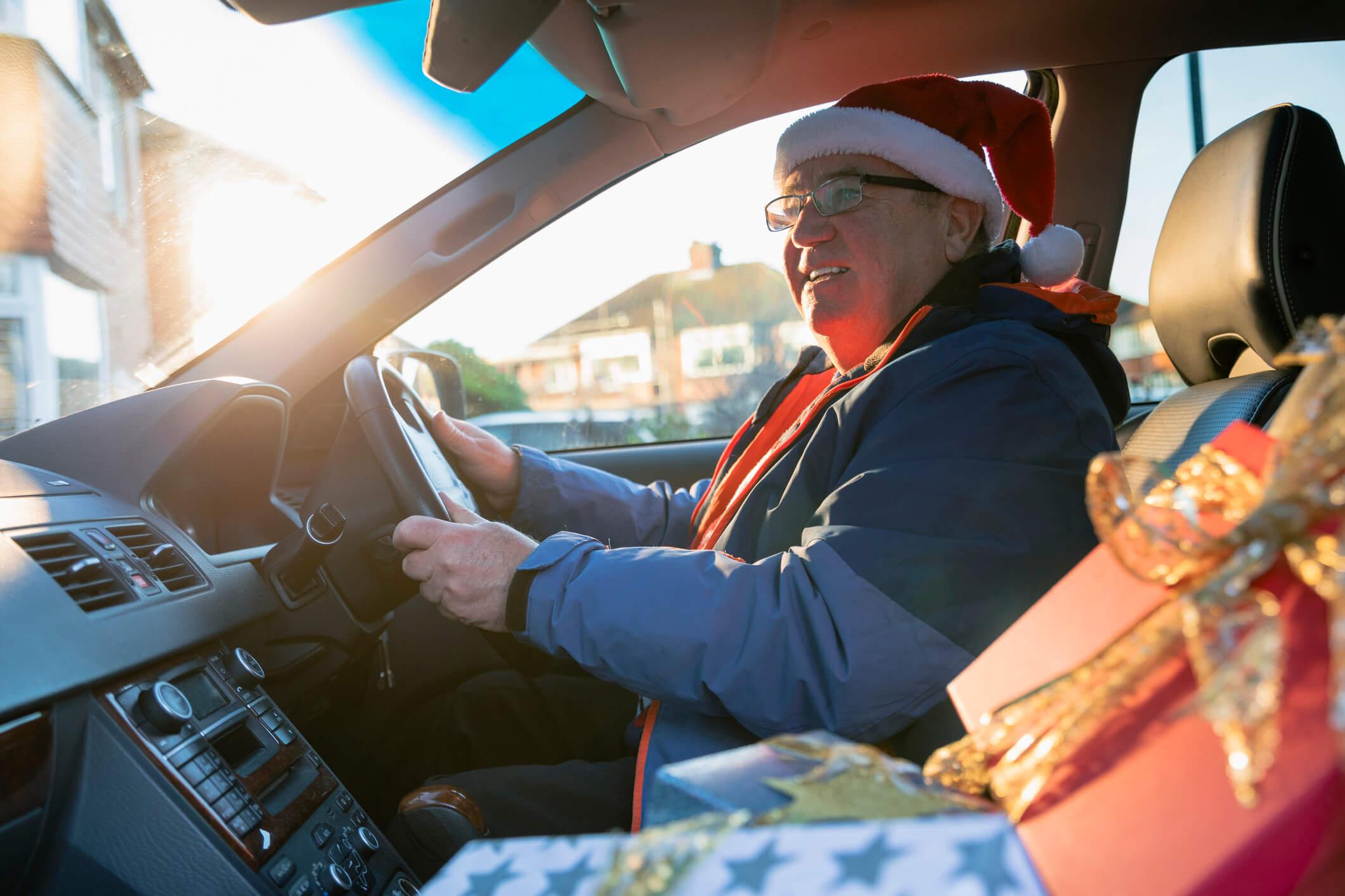 A man driving a car with a present in the front seat