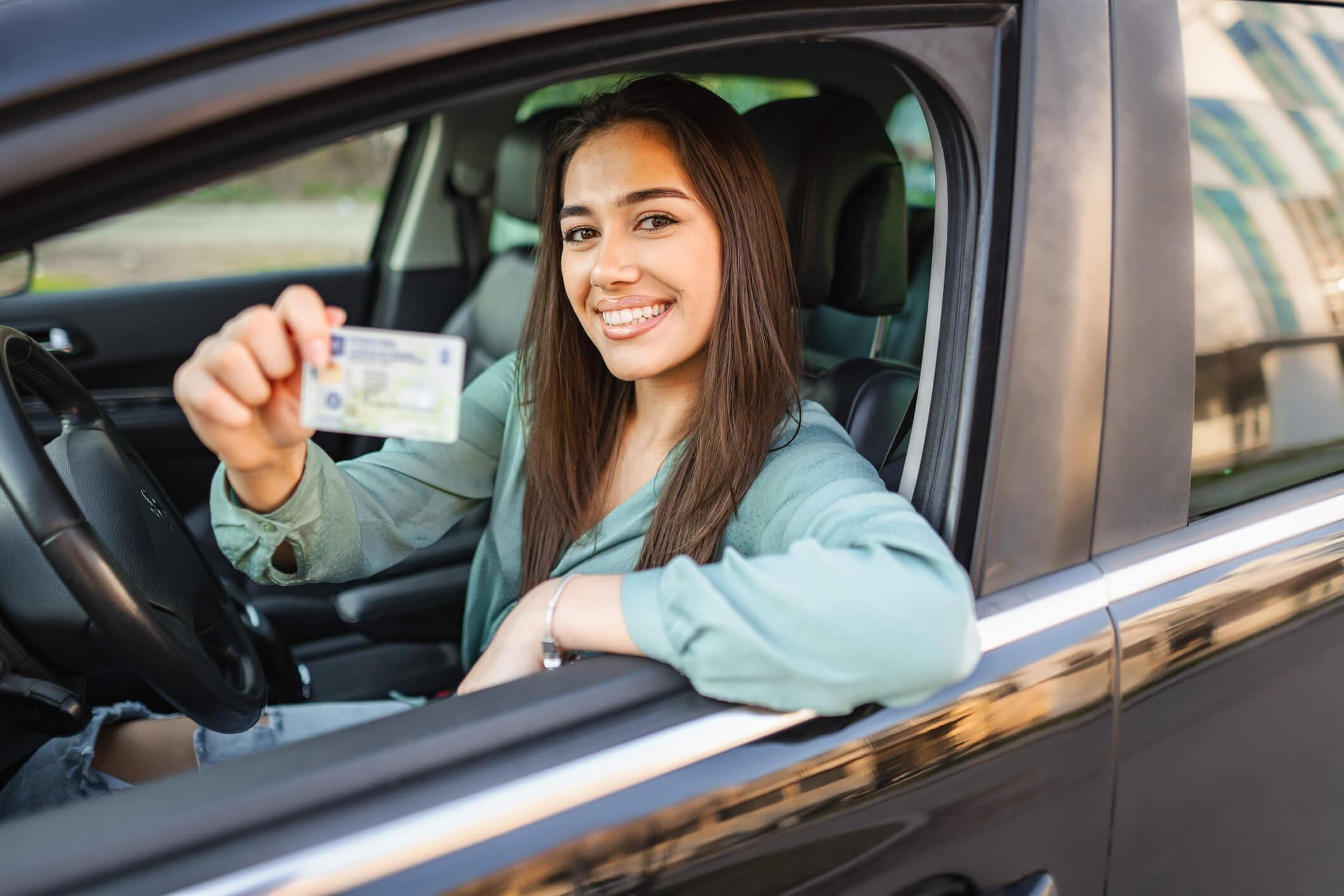 A smiling woman holding a driver's license