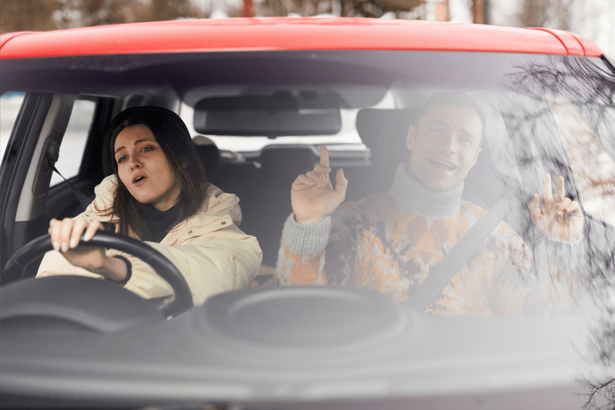 Two people singing in the car wearing winter clothes