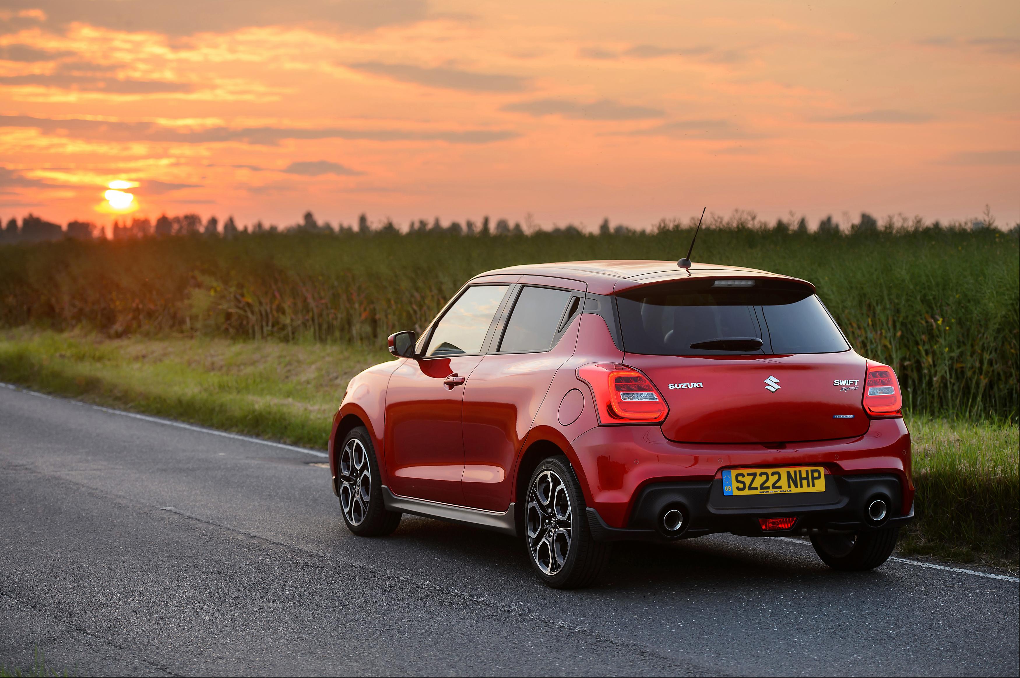 a red Suzuki Swift Sport Hybrid parked on the side of the road