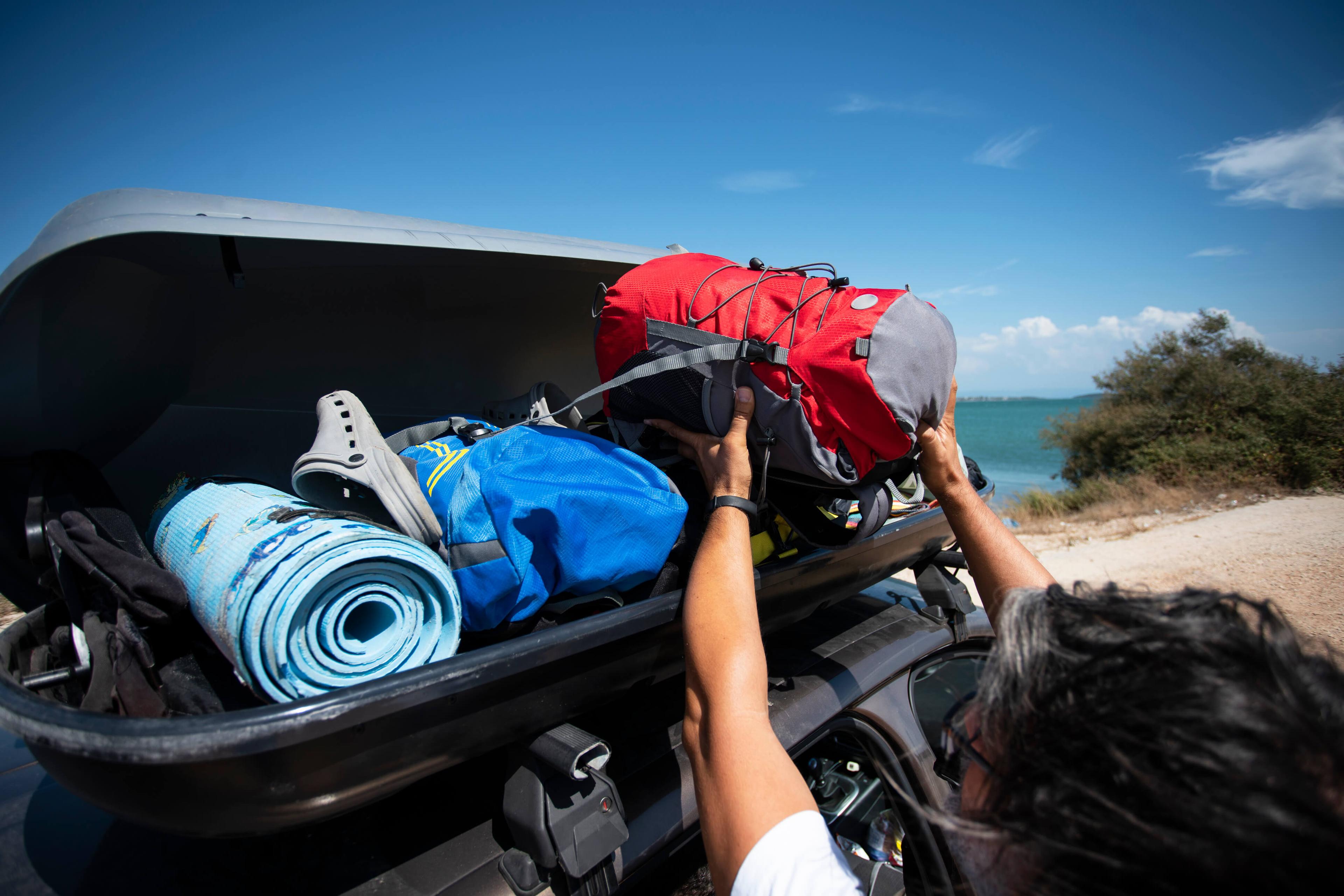 A person packing a roof box on a car roof