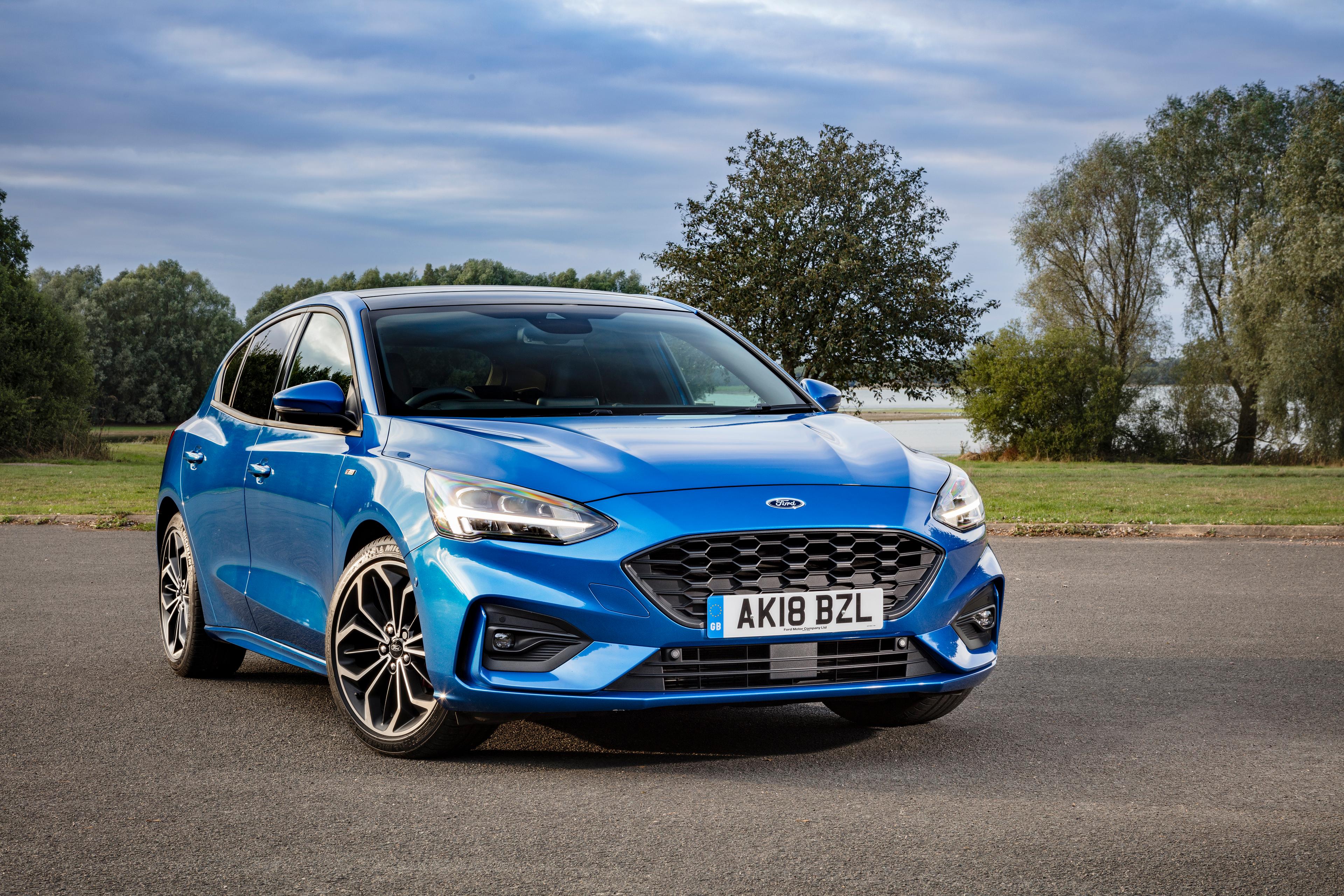 a dark blue ford focus parked on tarmac in front of trees