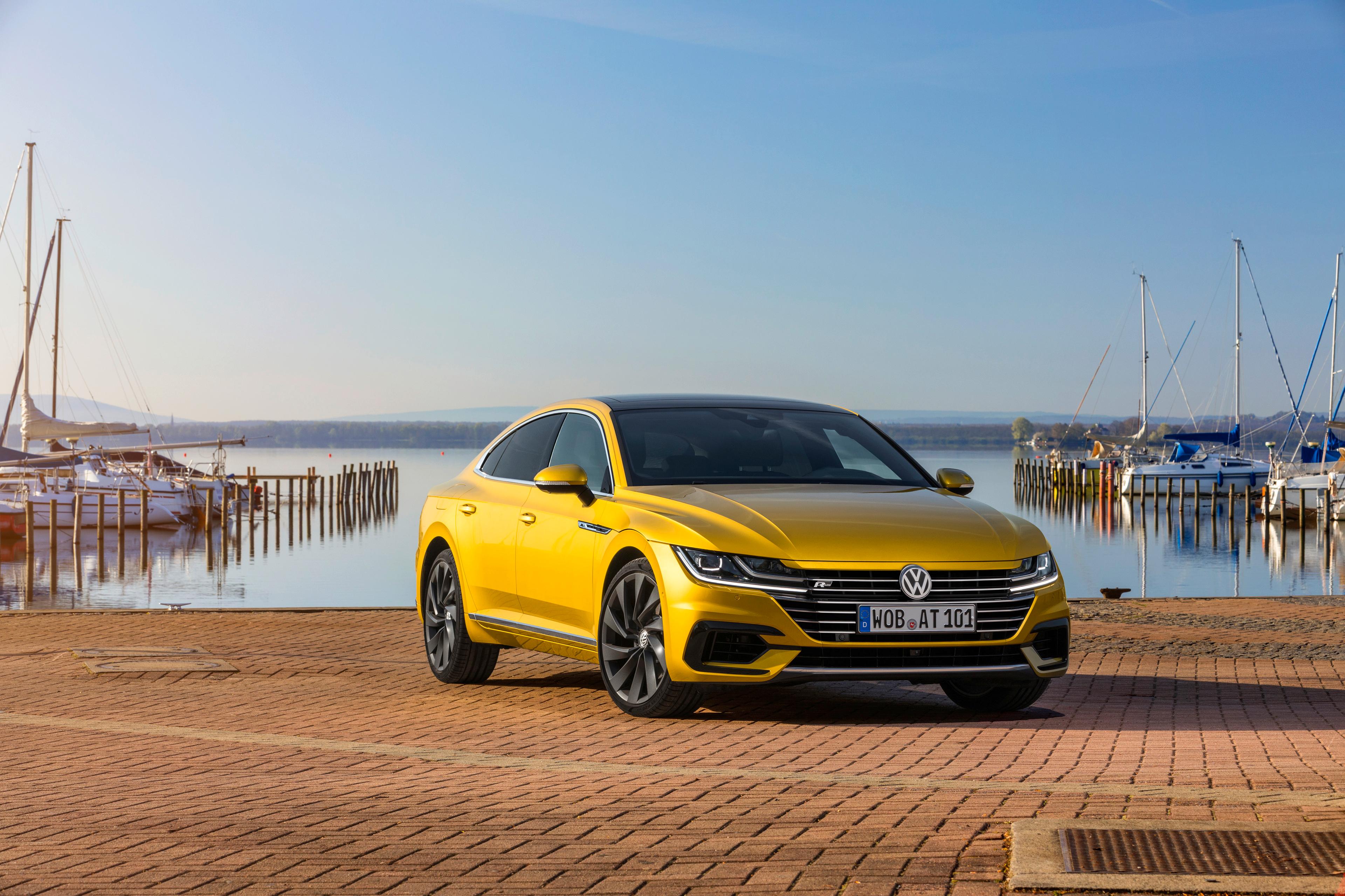 a gold VW Arteon parked at a docks by the sea