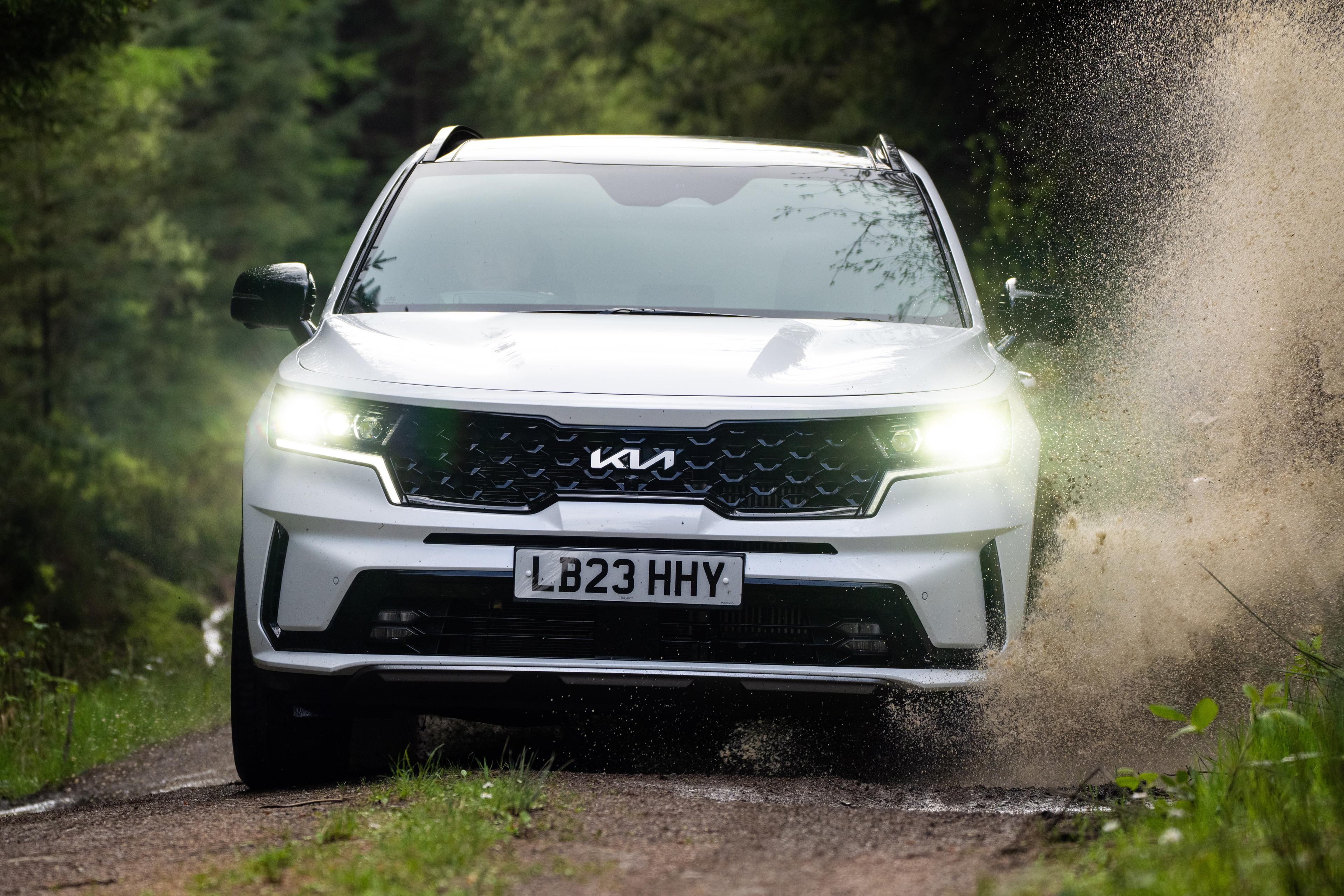 a white Kia Sorento plug-in hybrid driving on a muddy road