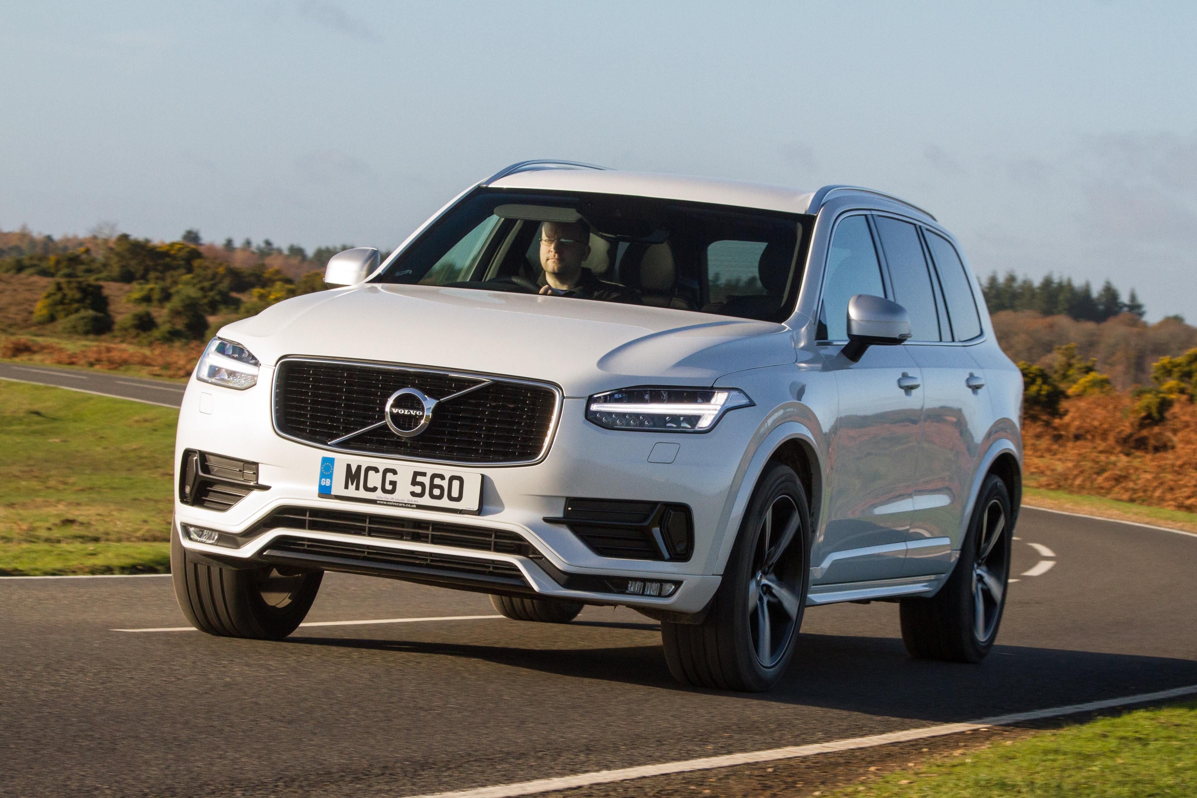 a white volvo xc90 driving on a country road