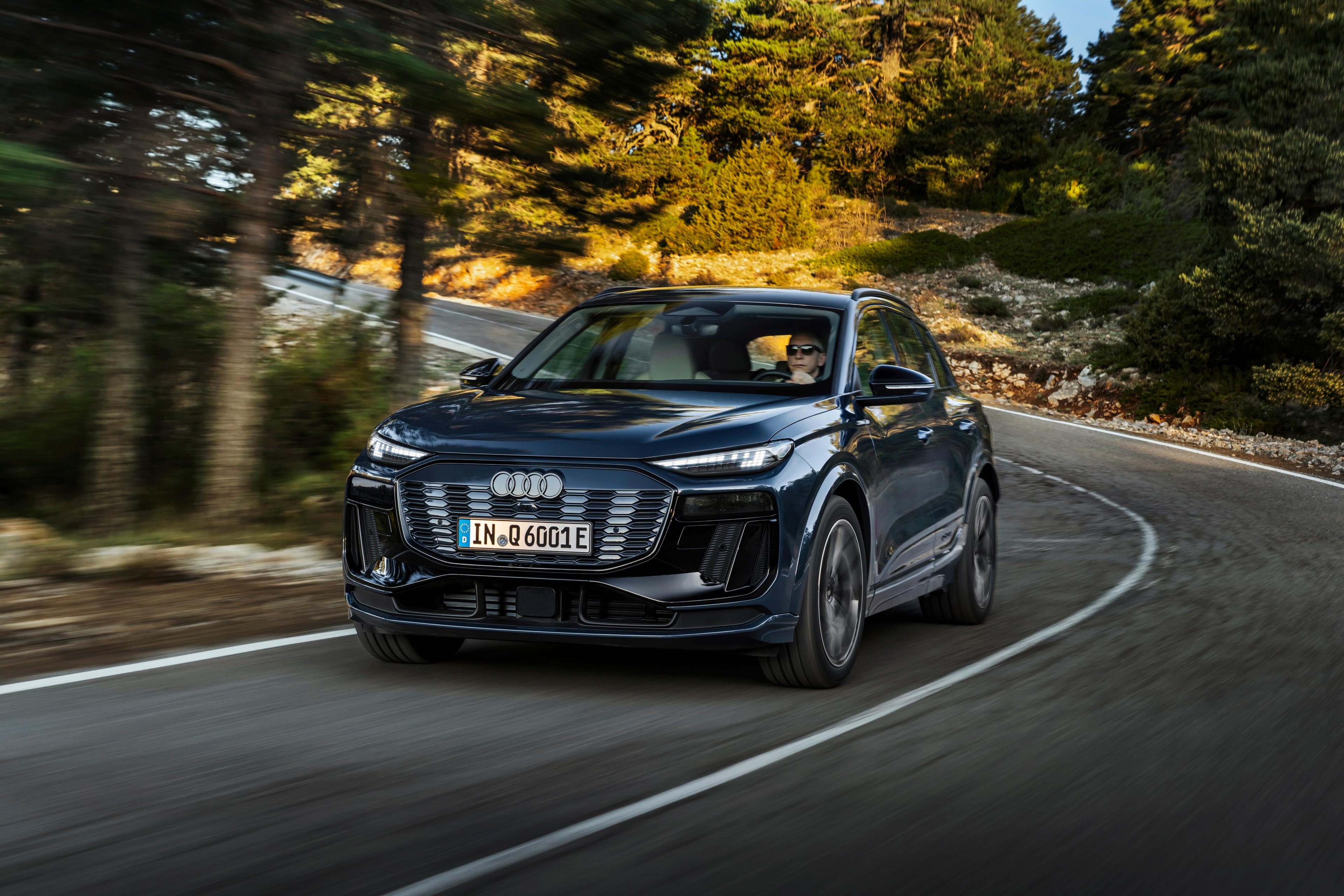 a black audi q6 e-tron driving on a country road