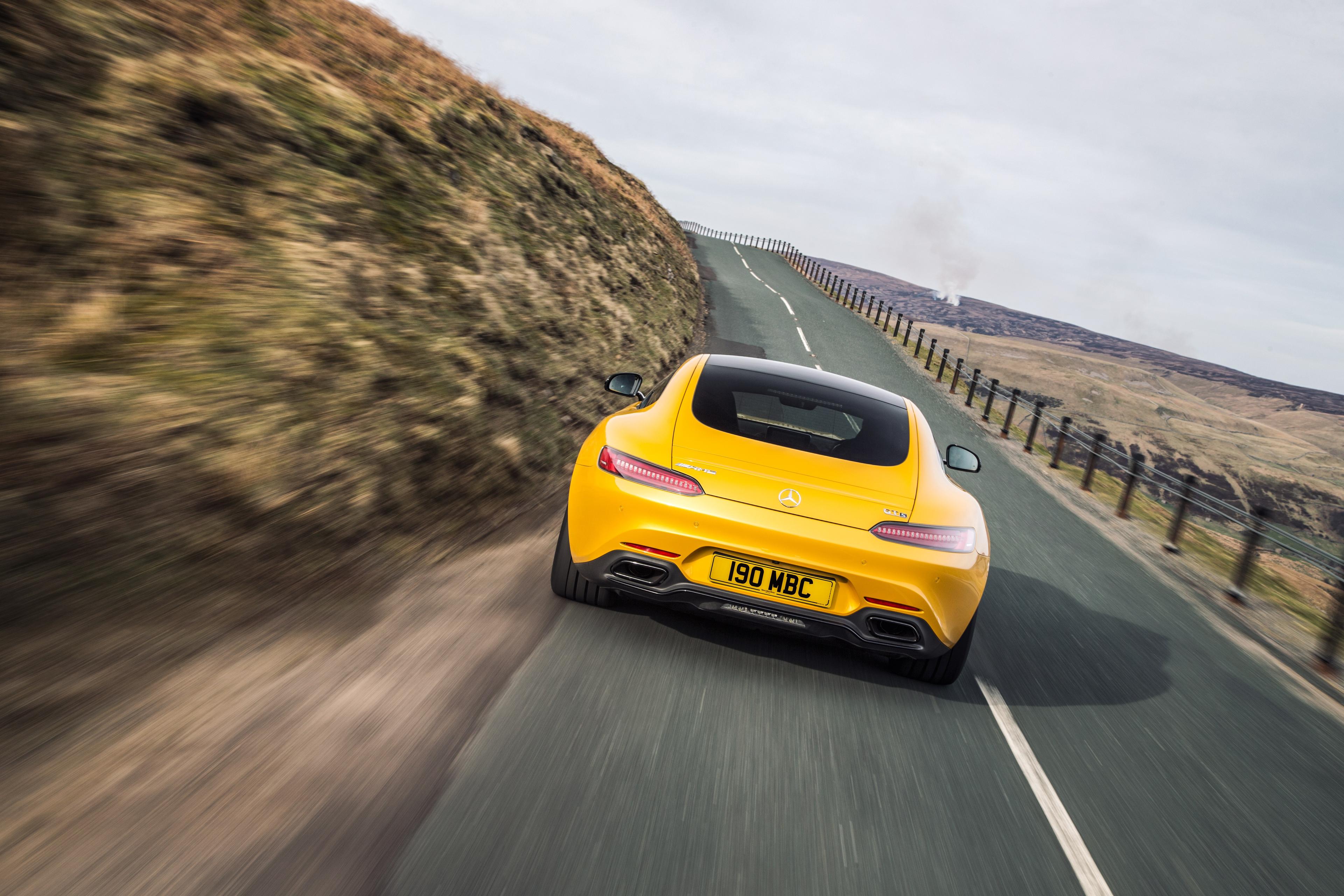 a yellow mercedes AMG GT's rear driving on a country road at speed