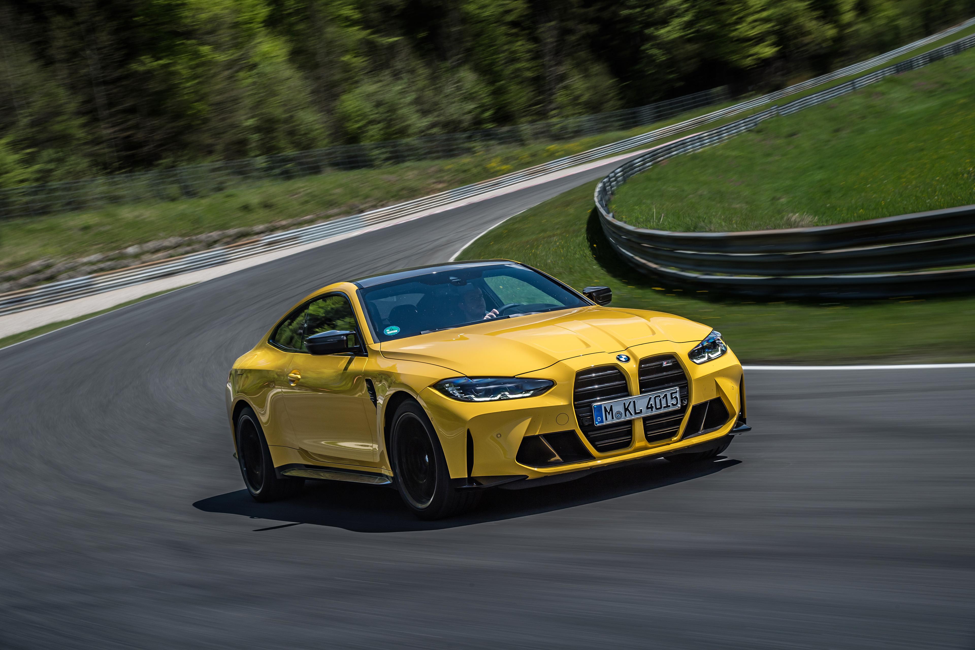 a yellow bmw m4 competition driving around the nurburgring race track