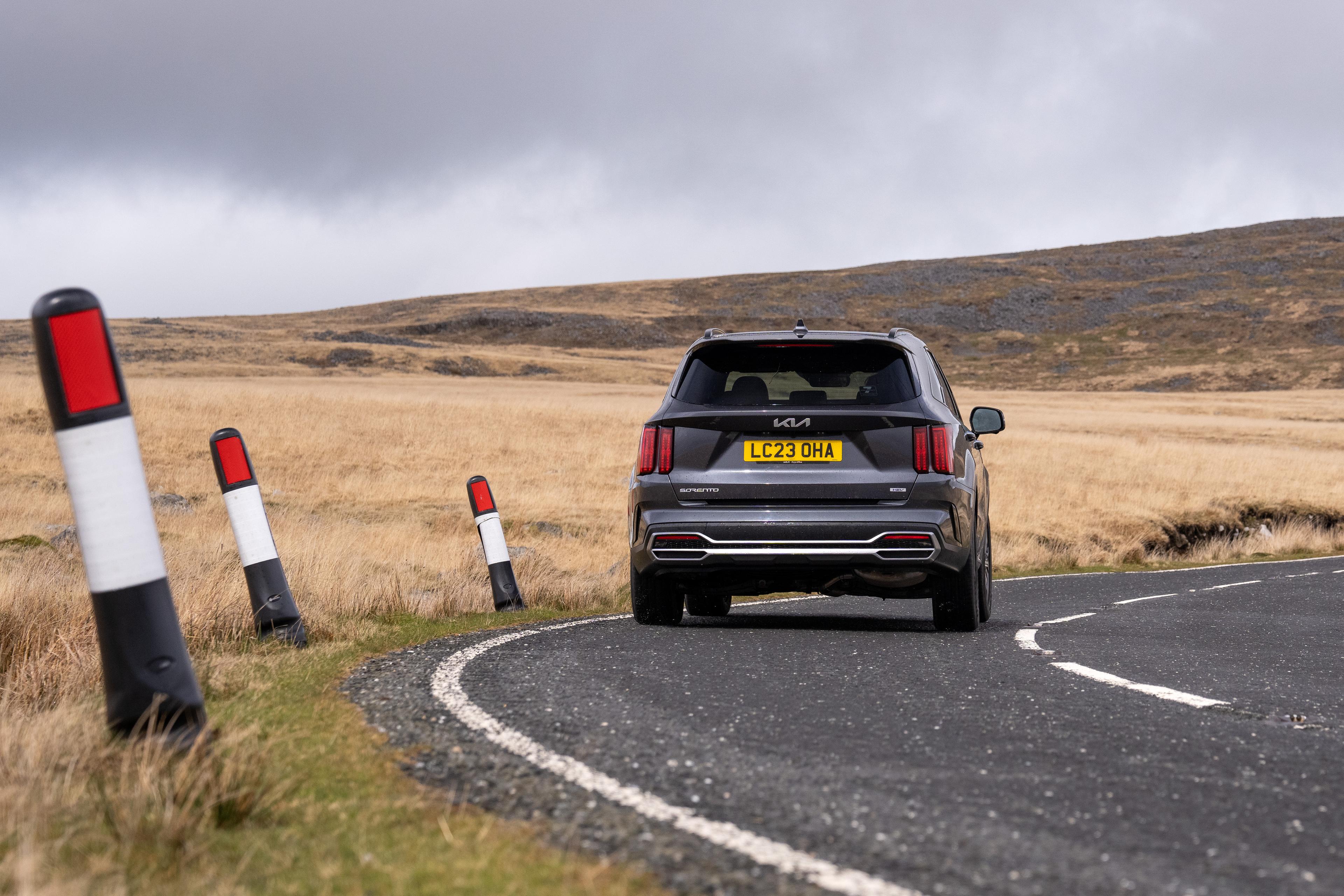 a grey kia sorento driving on a country road in the UK