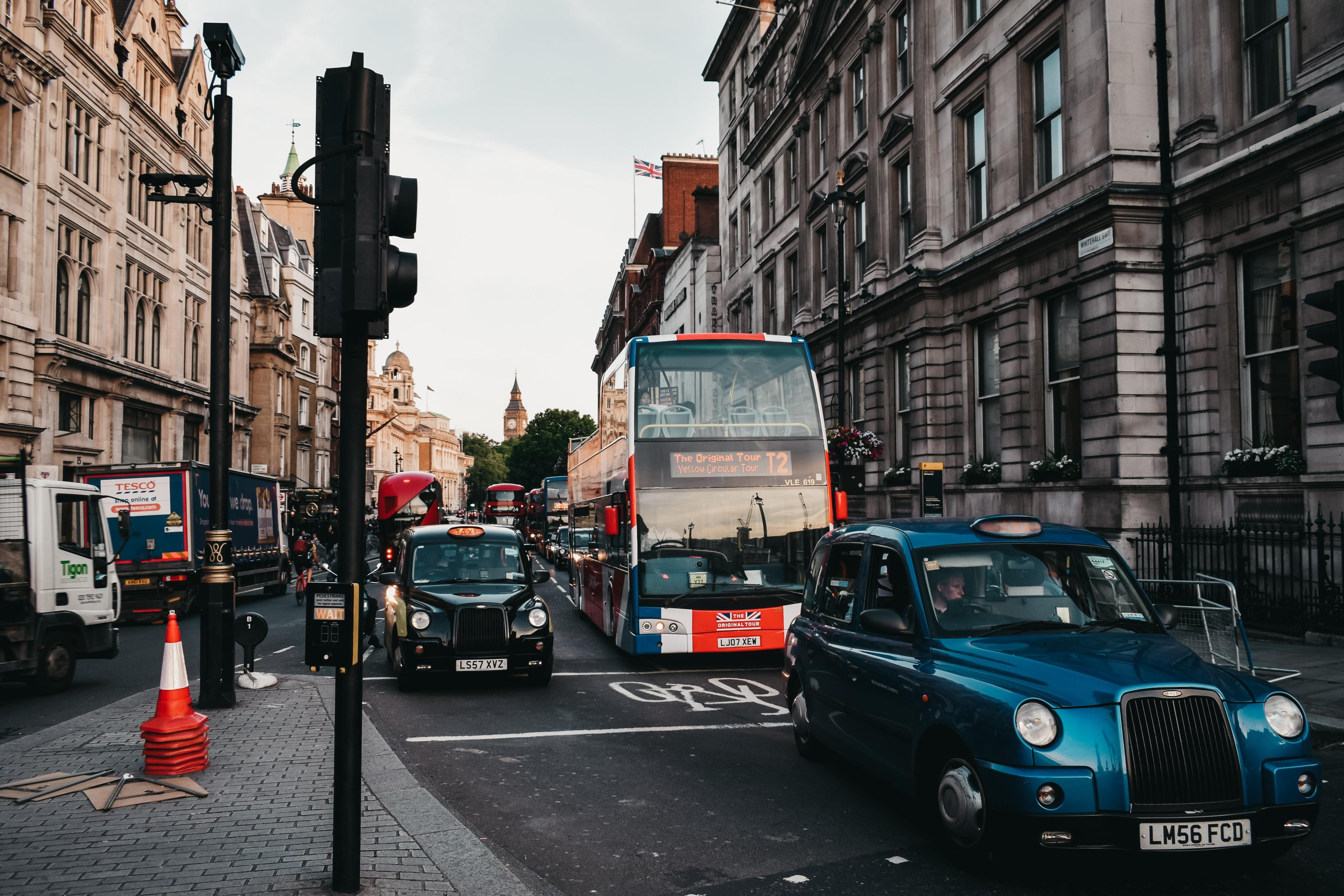 a busy london street with two taxis and a bus