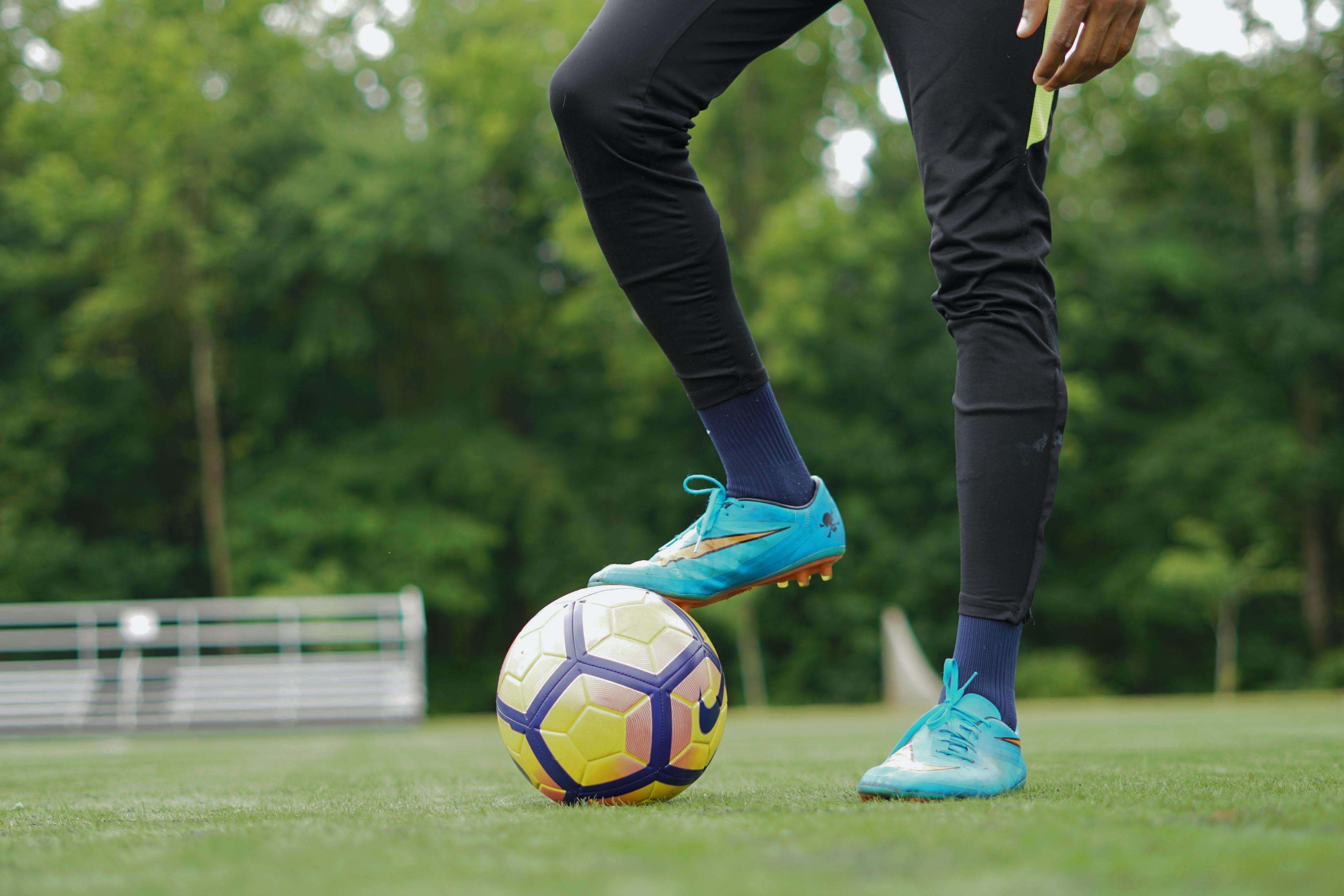 A man wearing blue football boots stood on a football