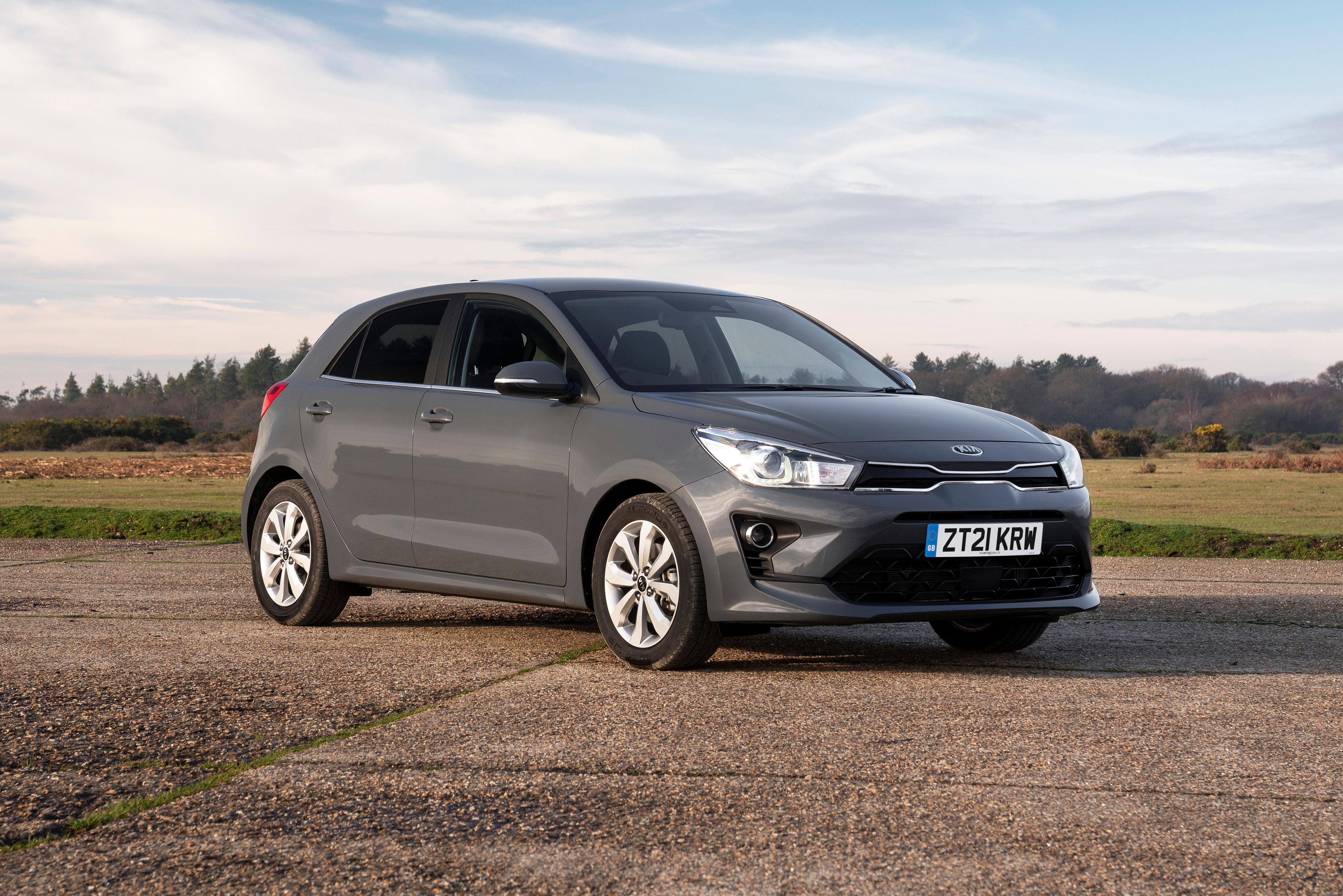 a grey kia rio parked next to a field