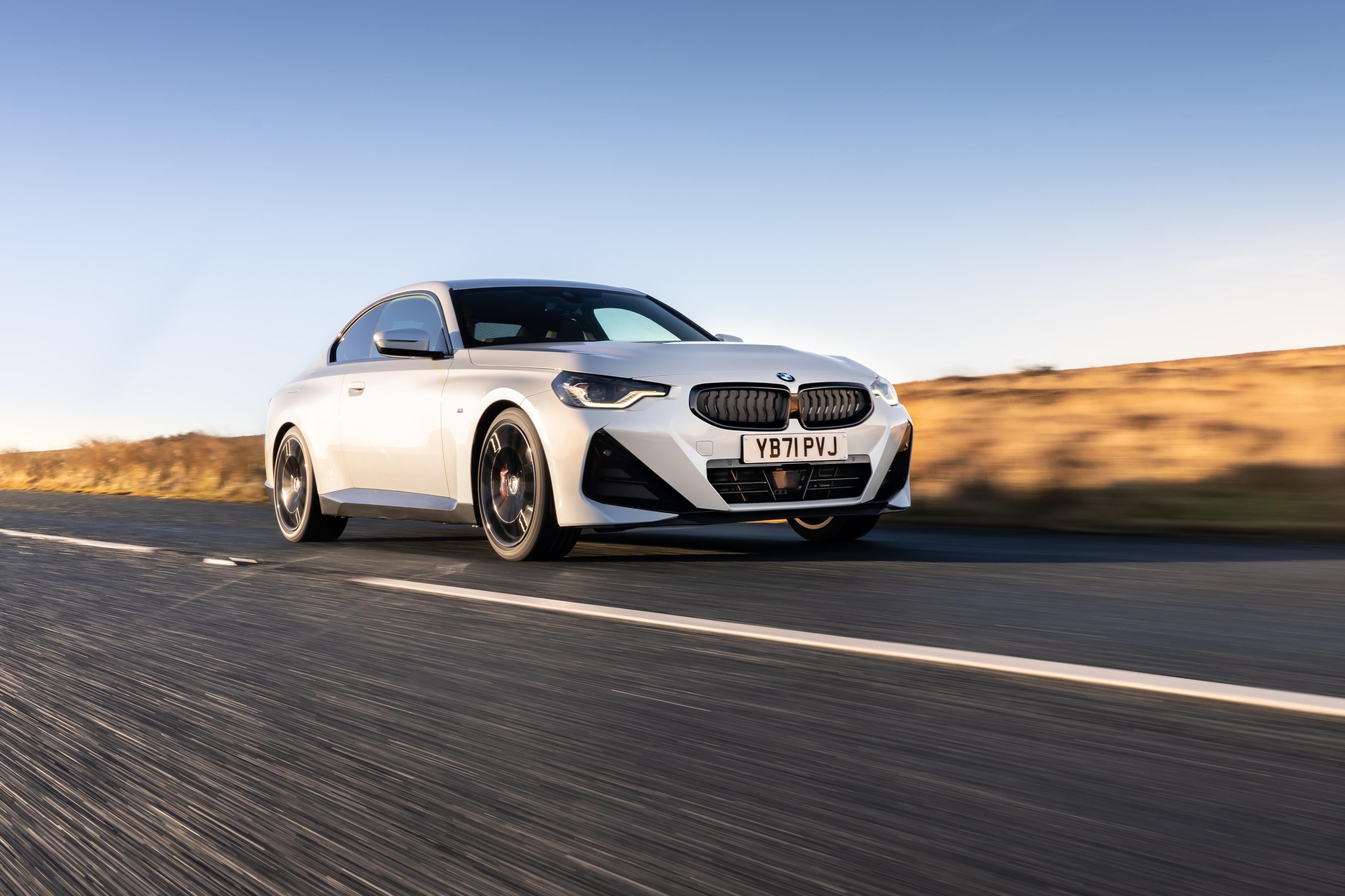 A white BMW 2 Series driving on a road