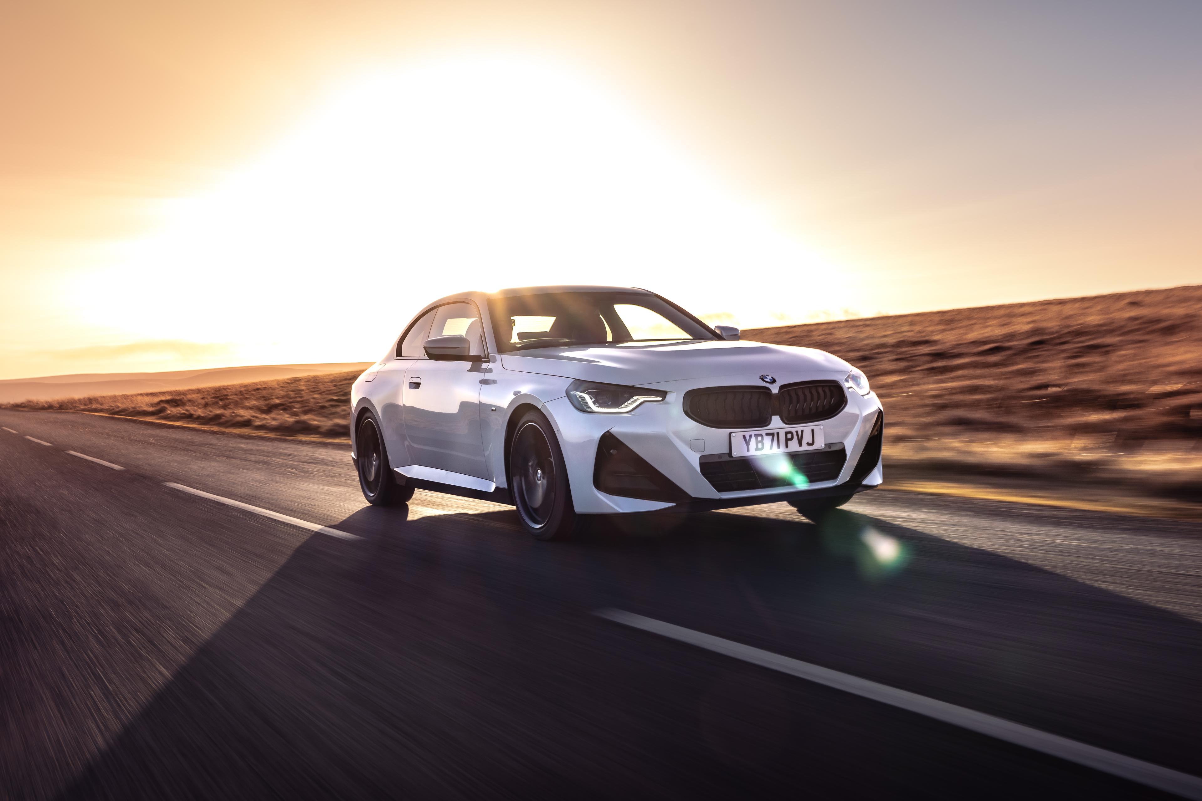 A white BMW 2 Series Coupe driving in the sun