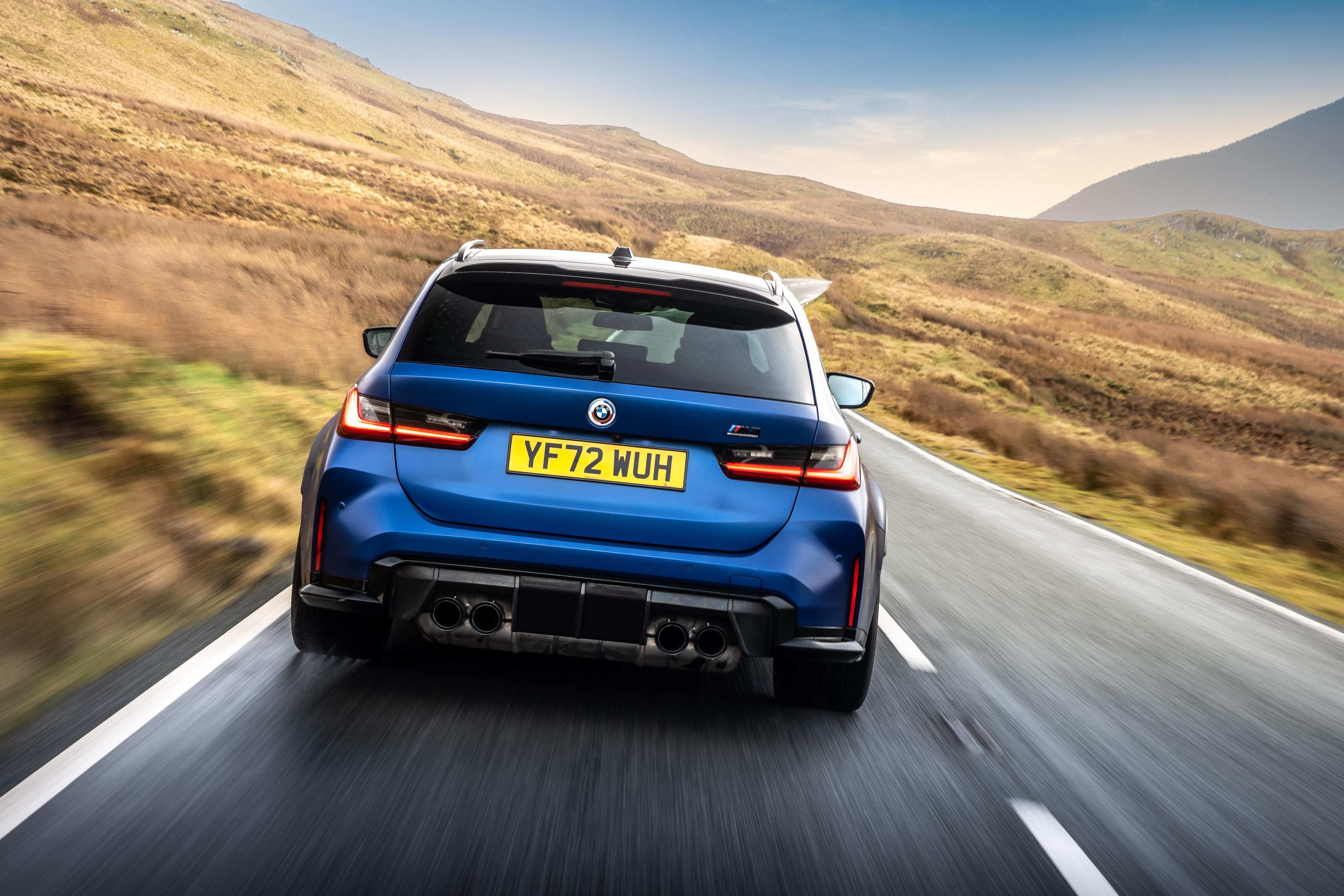 a blue BMW M3 Touring driving on a country road in wales