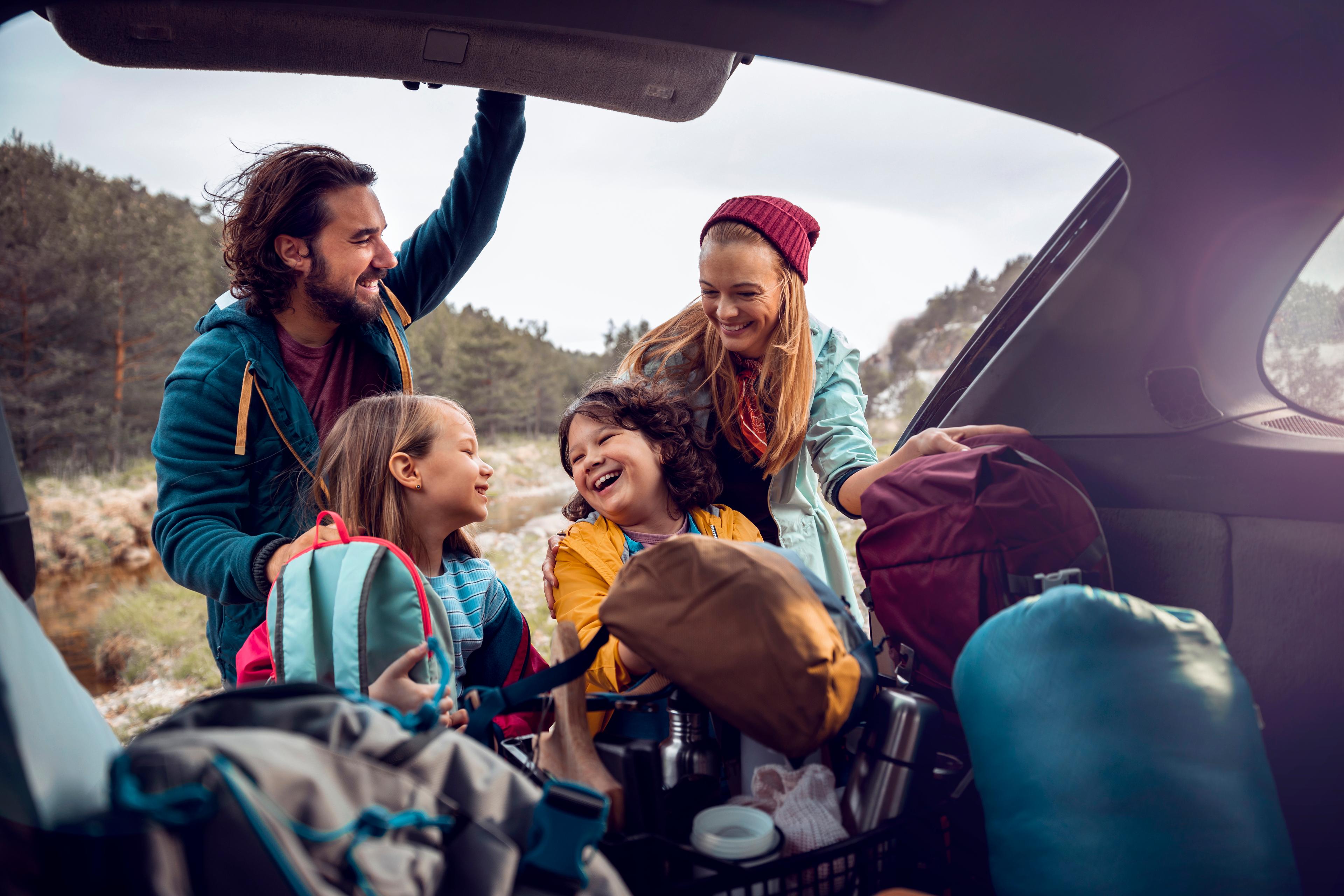 A family are smiling and laughing as they unpack their car