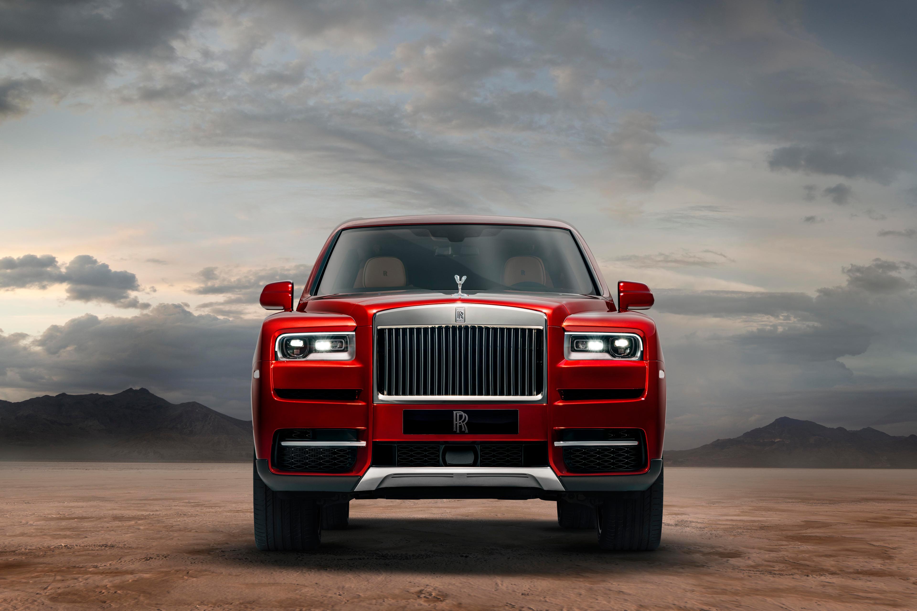 a red rolls-royce cullinan parked in the desert